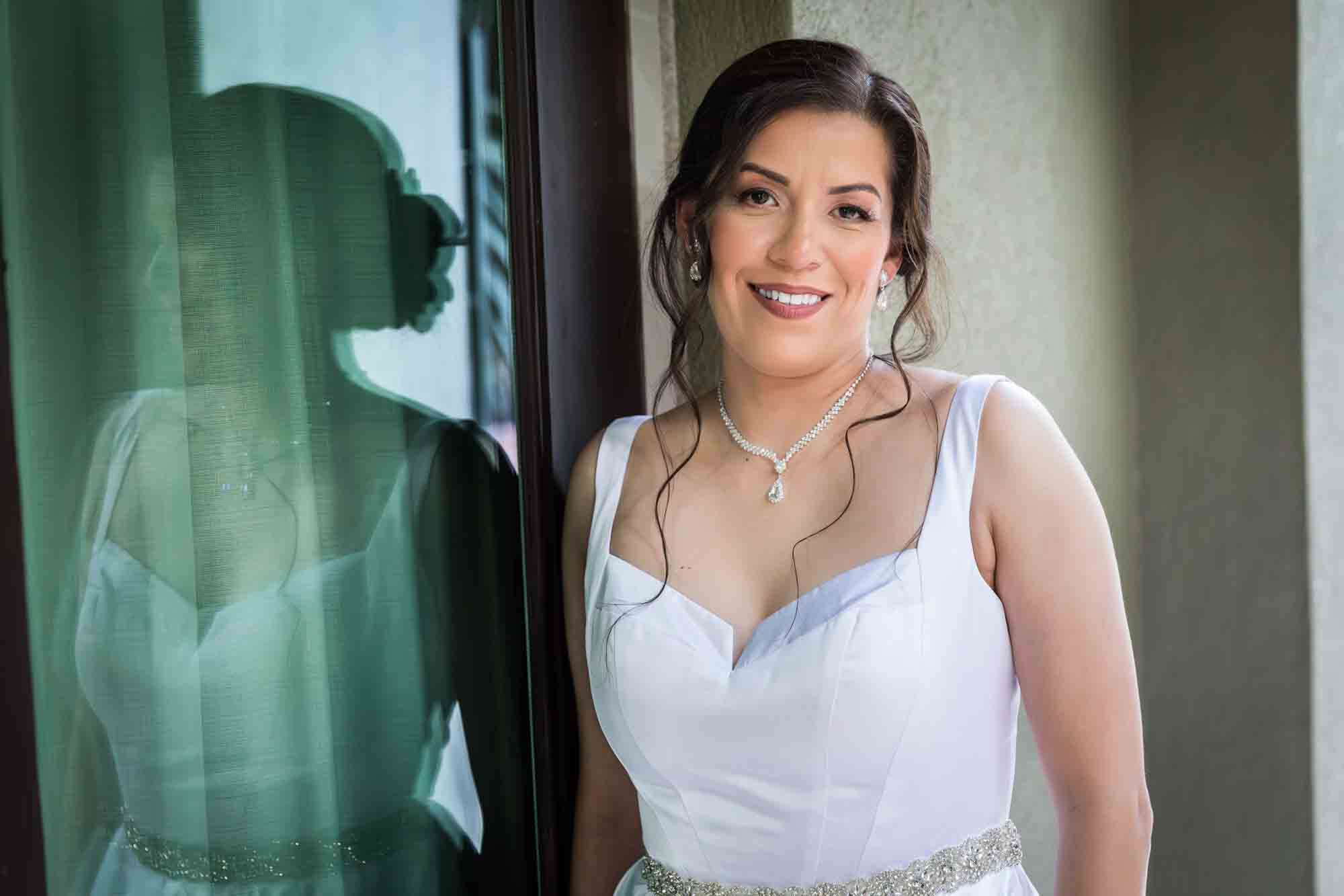 Bride wearing sleeveless, white dress reflected in window during a downtown San Antonio bridal portrait session