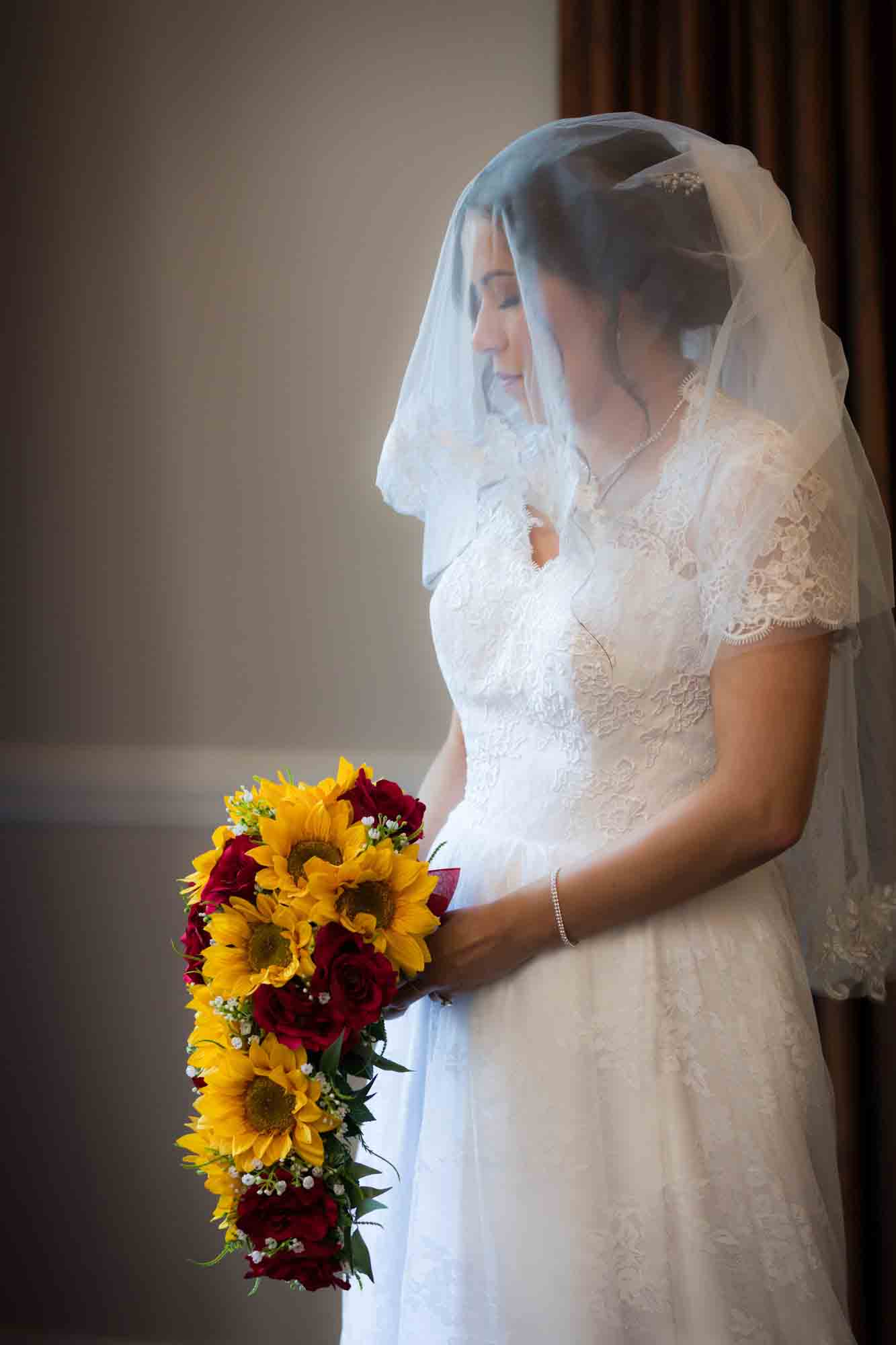 Bride with veil covering face holding flower bouquet during a Hotel Contessa bridal portrait session in downtown San Antonio