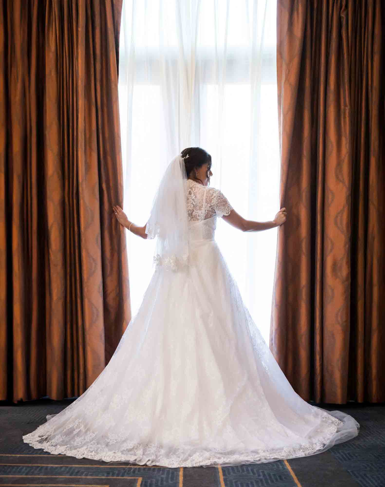 Bride wearing white dress and holding curtains during a Hotel Contessa bridal portrait session in downtown San Antonio