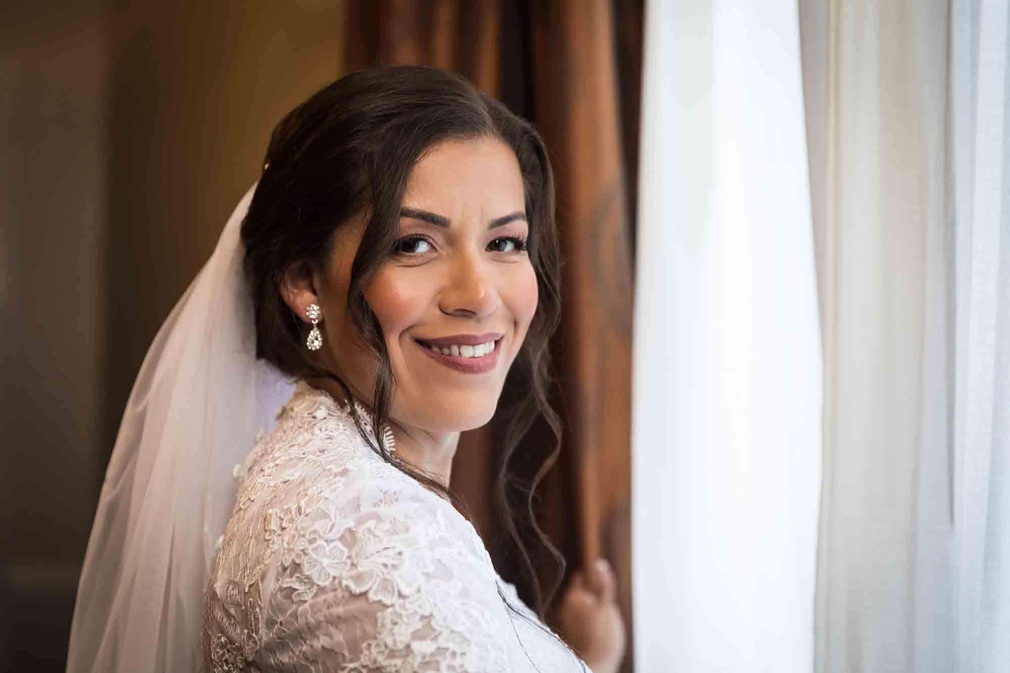 Bride wearing veil next to window and curtains during a Hotel Contessa bridal portrait session in downtown San Antonio