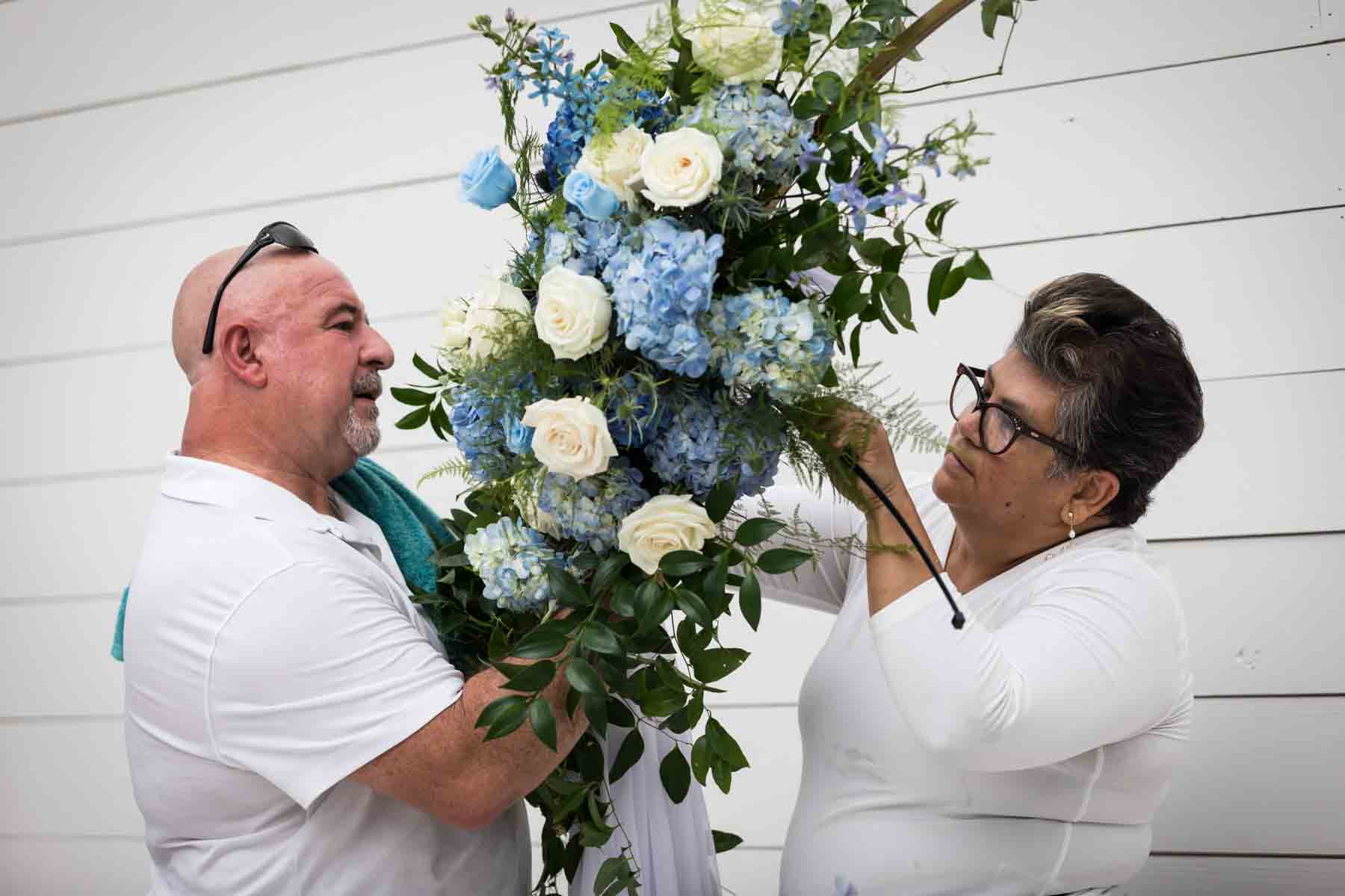 Floral team at Ay Poppy! putting together a white and blue floral wedding ceremony arrangement for an article on how to choose the perfect flowers for your wedding or event