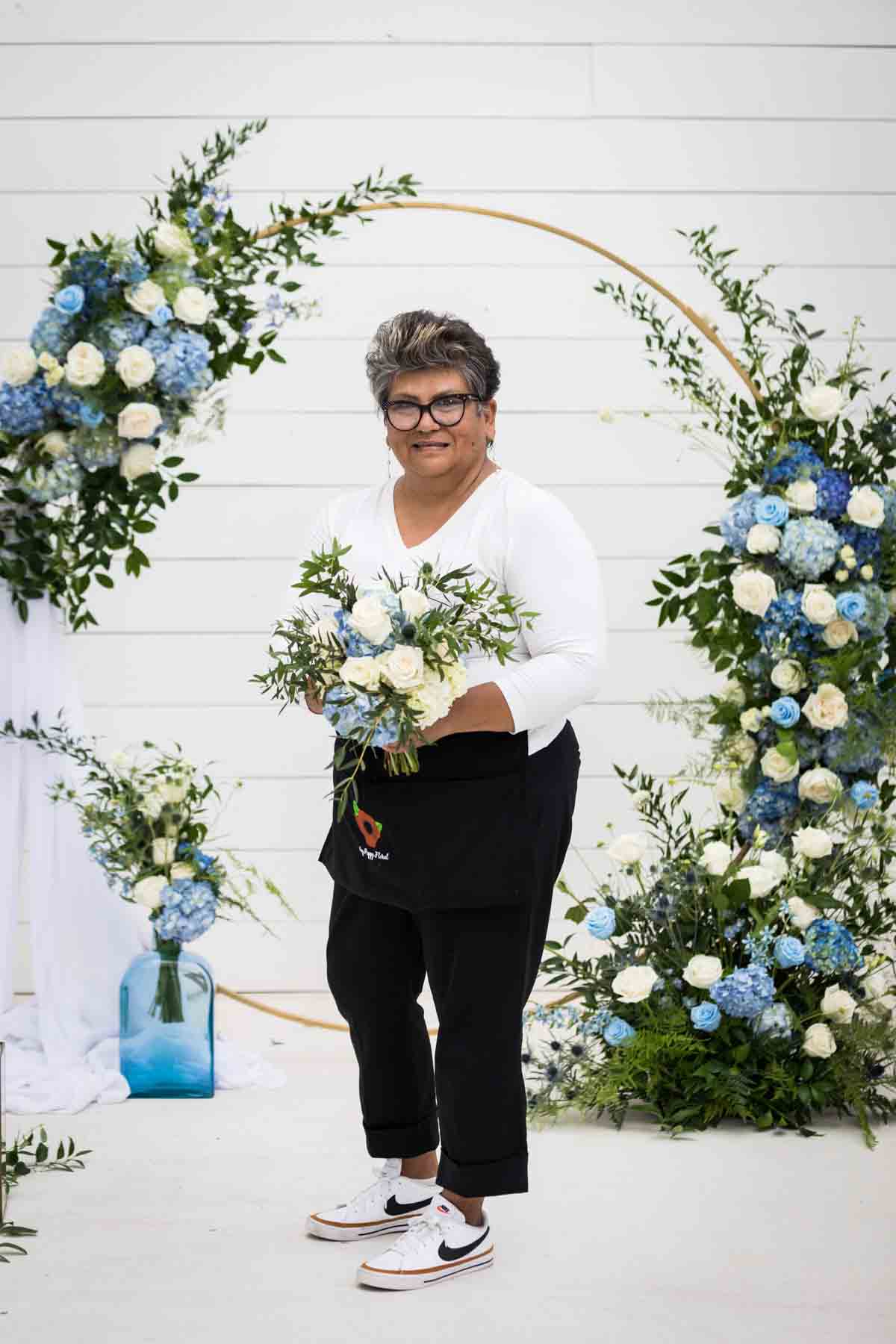 Cici of Ay Poppy! Floral and Event Decor holding a white and blue bridal bouquet for an article on how to choose the perfect flowers for your wedding or event