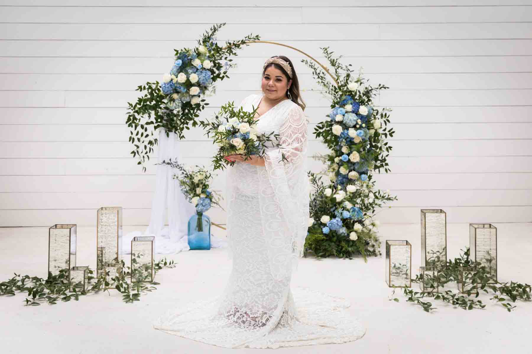 Bride with long sleeves holding a white and blue bridal bouquet for an article on how to choose the perfect flowers for your wedding or event