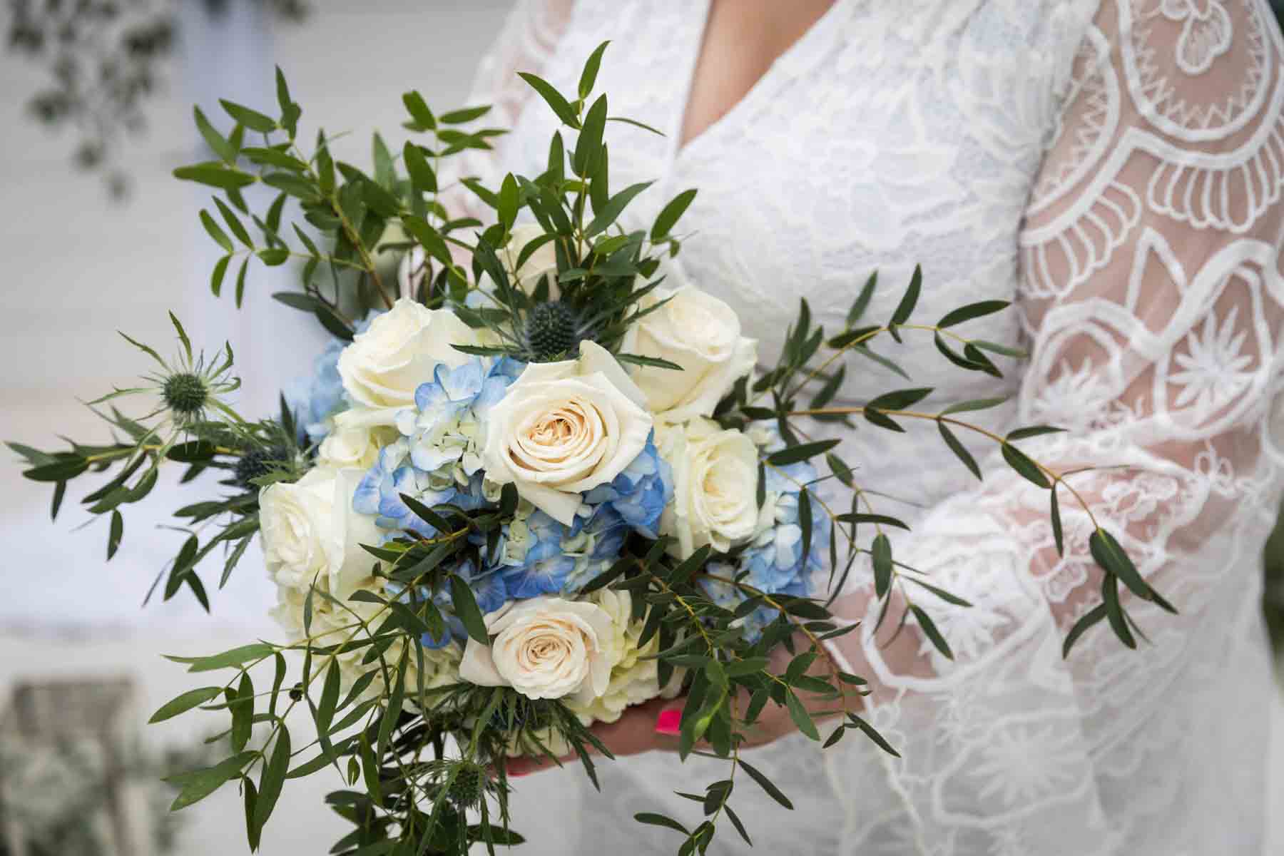 Close up of bride holding a white and blue bridal bouquet