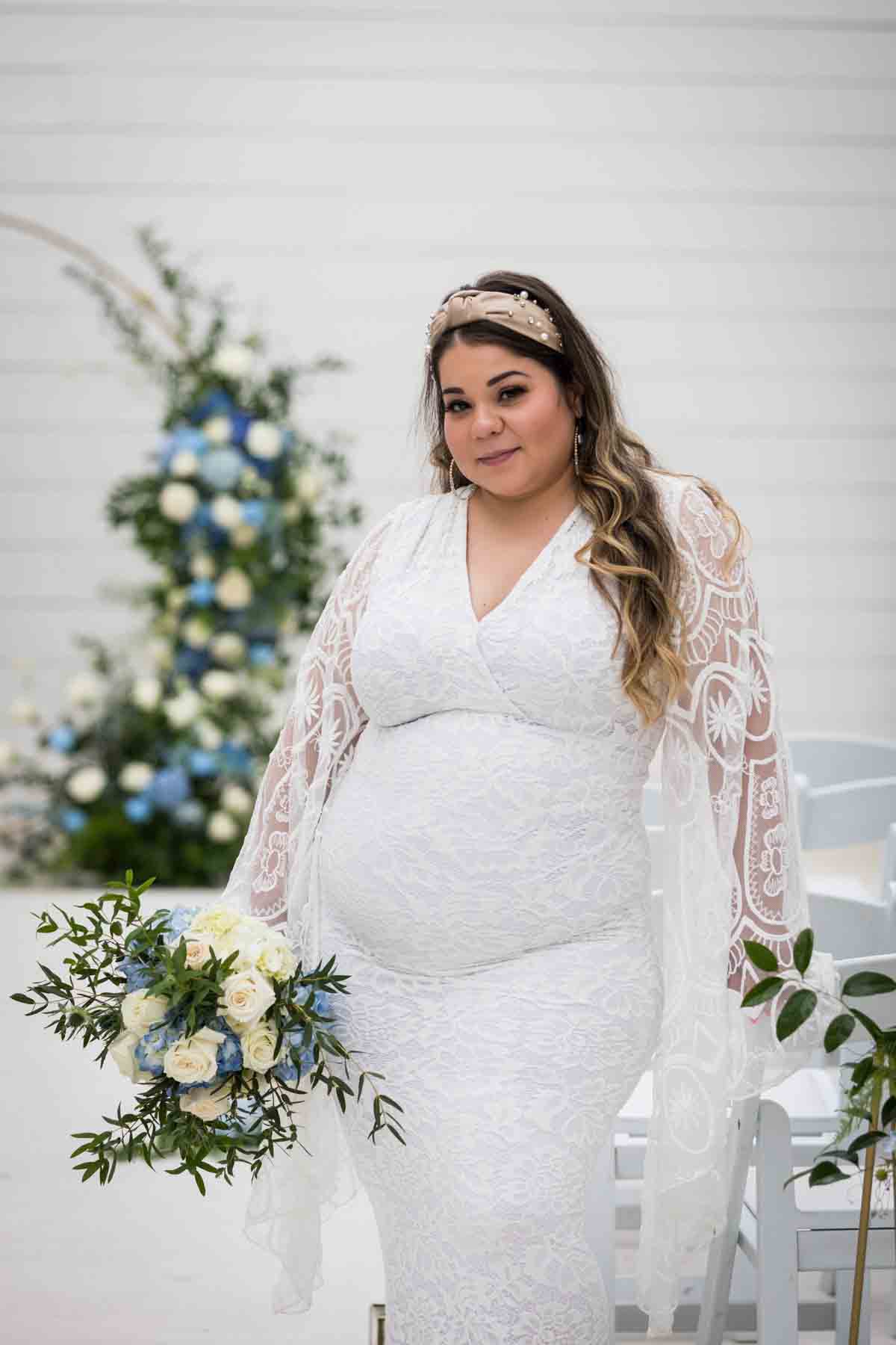 Bride with long sleeves holding a white and blue bridal bouquet for an article on how to choose the perfect flowers for your wedding or event