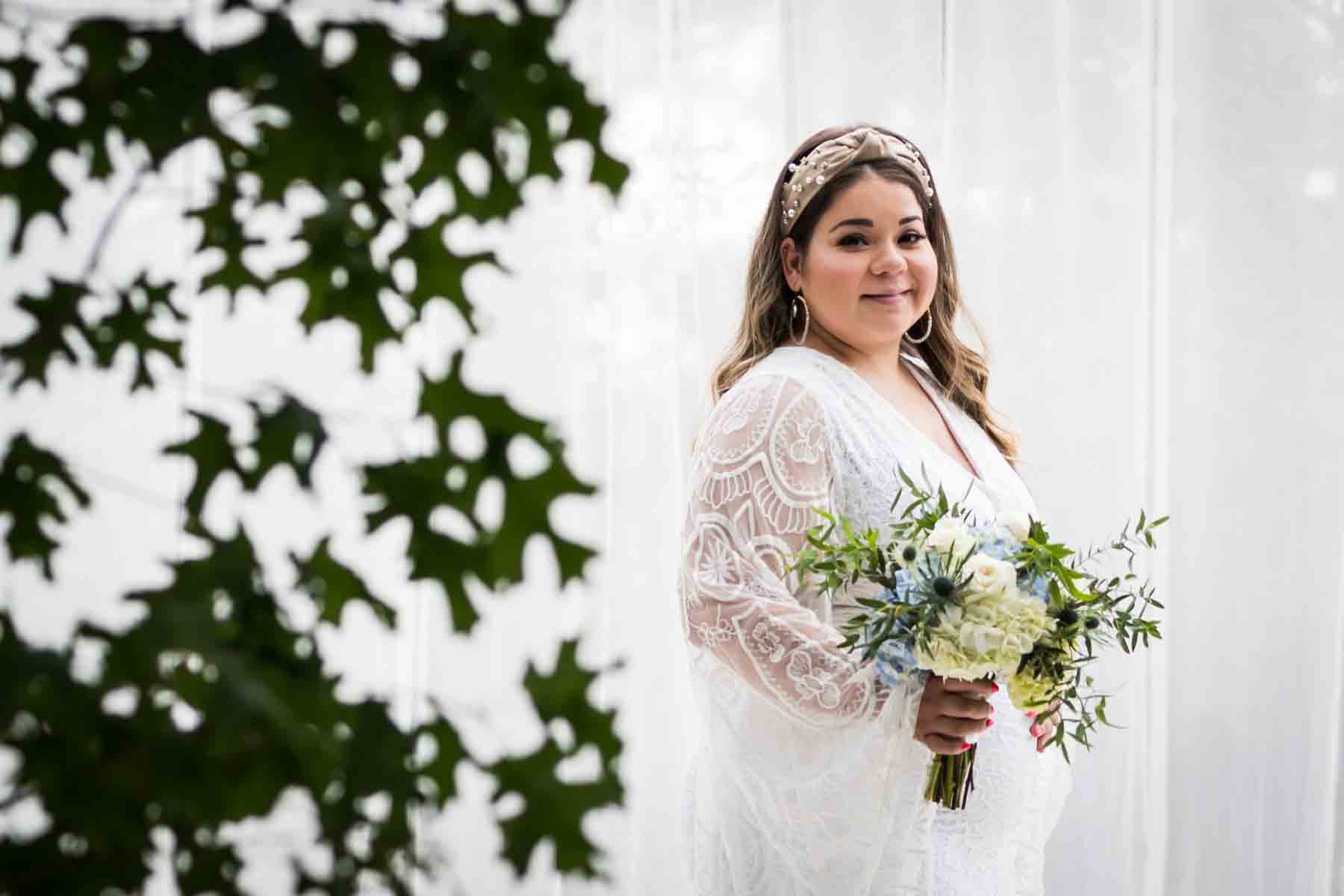 Bride with long sleeves holding a white and blue bridal bouquet for an article on how to choose the perfect flowers for your wedding or event