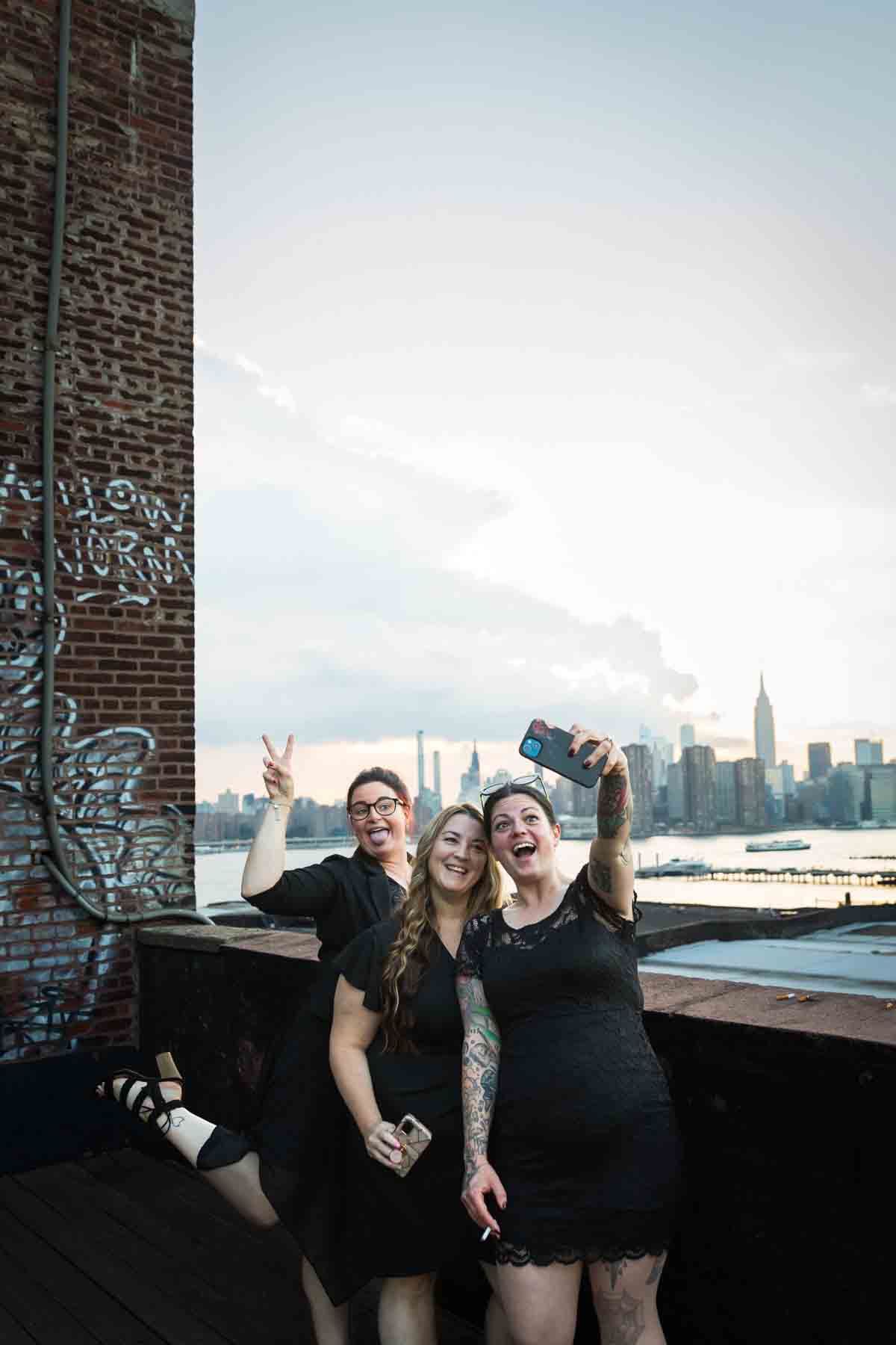 Three guests on a rooftop taking a selfie at a wedding reception for an article on how to take the perfect selfie