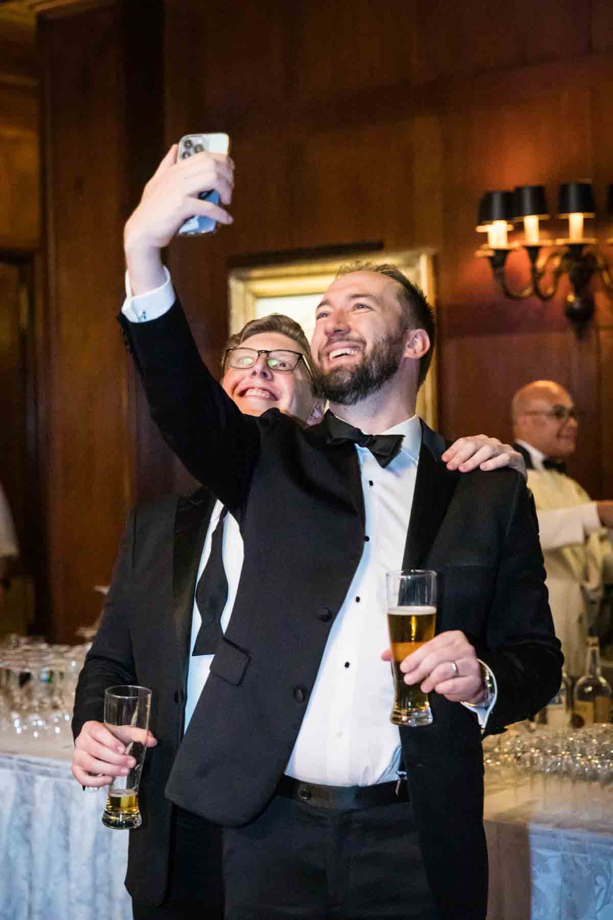 Two men wearing tuxedos taking a selfie at a wedding reception for an article on how to take the perfect selfie