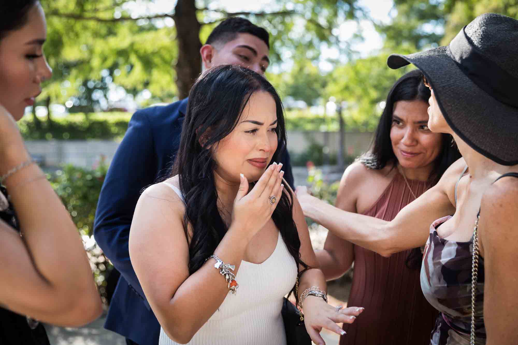 Woman with long brown hair holding hand to face for an article on Pearl surprise proposal tips