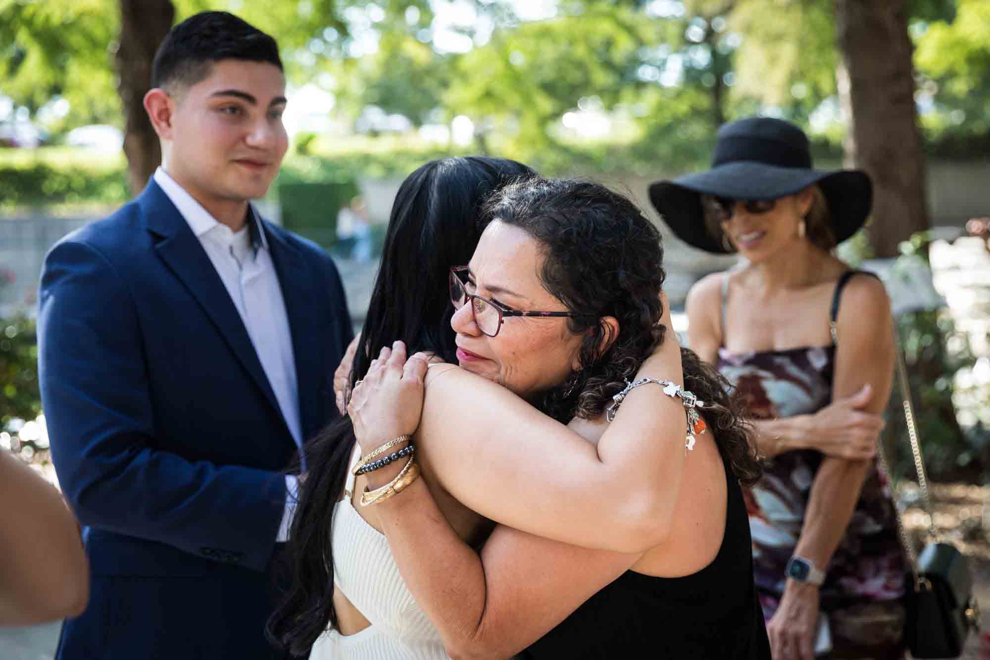 Two women hugging in front of family for an article on Pearl surprise proposal tips