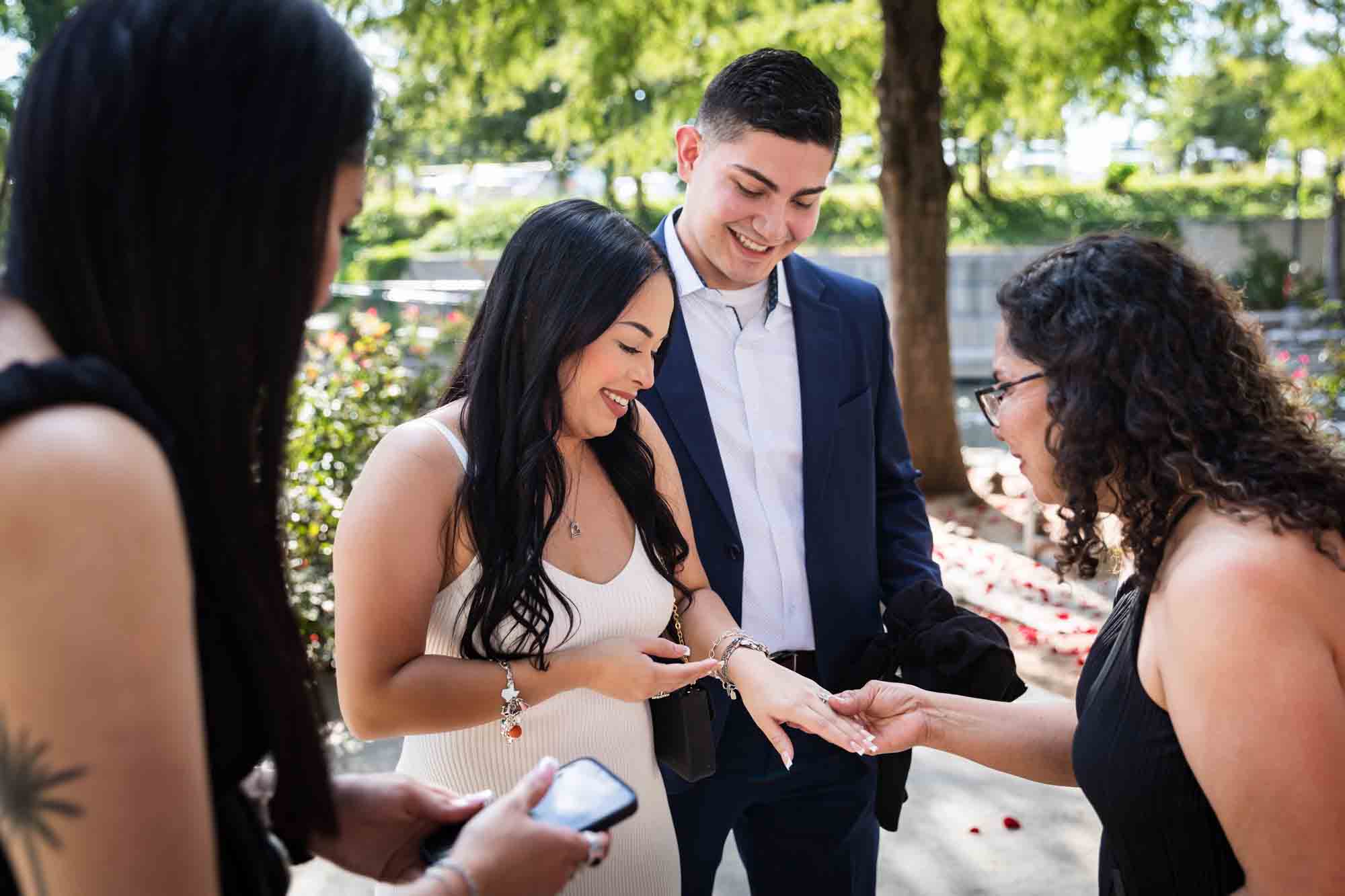 Couple showing woman's hand wearing engagement ring to family for an article on Pearl surprise proposal tips