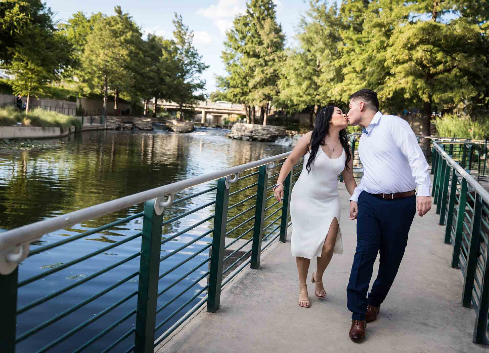 Couple kissing while walking on pathway beside River Walk for an article on Pearl surprise proposal tips