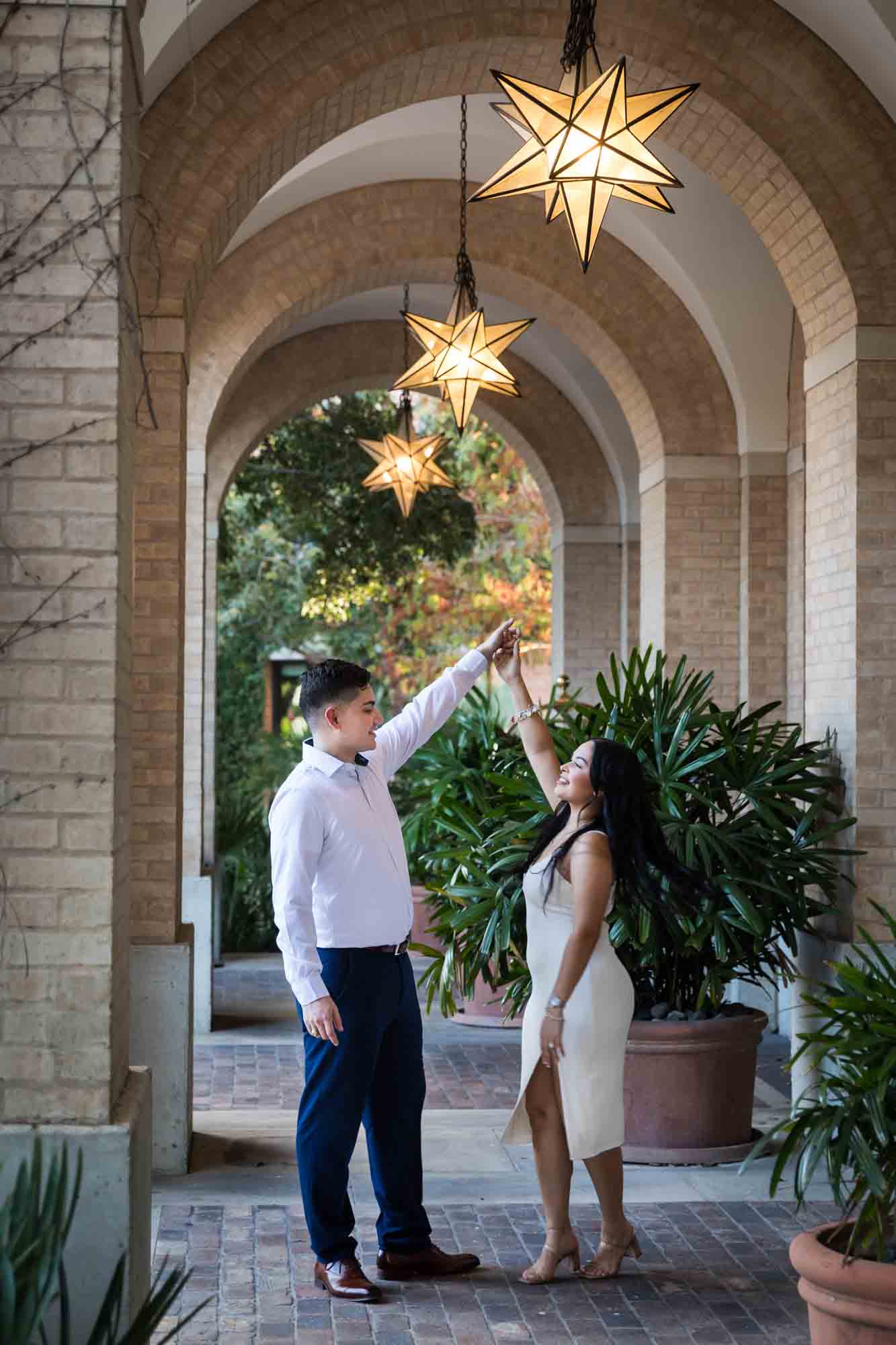 Couple dancing in arched walkway in front of palm leaves for an article on Pearl surprise proposal tips