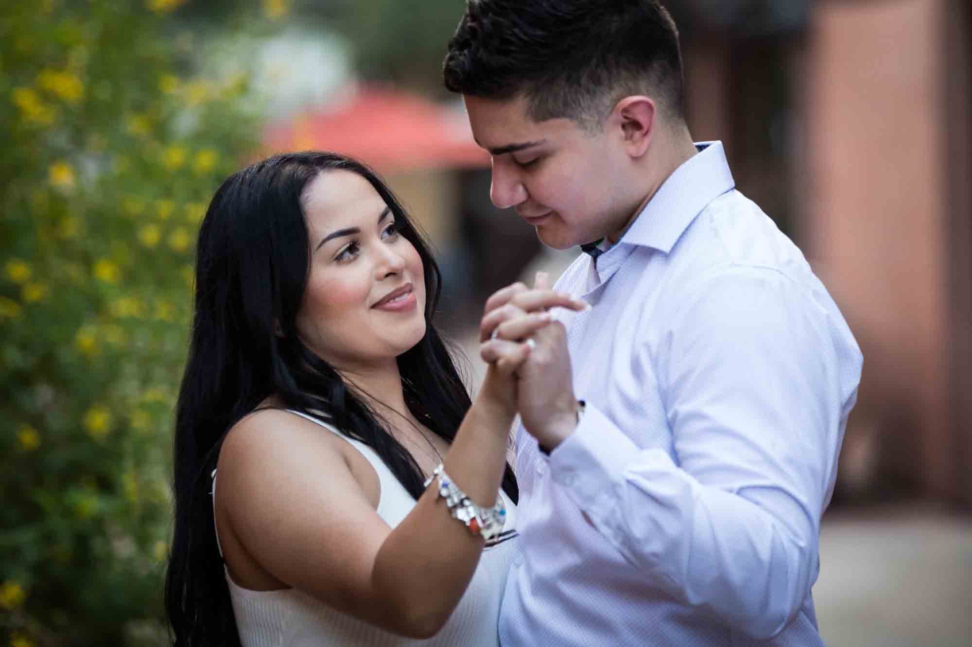 Couple dancing in front of bush with yellow flowers for an article on Pearl surprise proposal tips