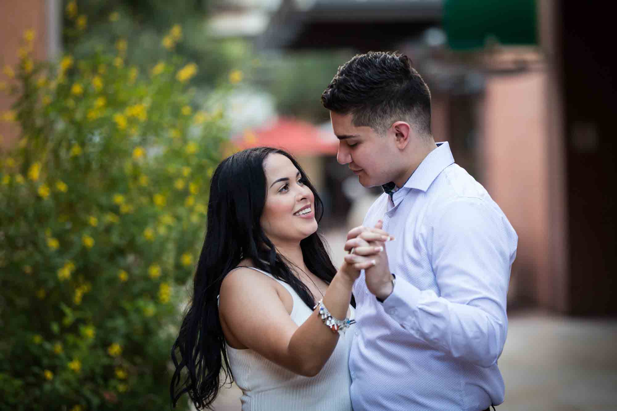 Couple dancing in front of bush with yellow flowers for an article on Pearl surprise proposal tips