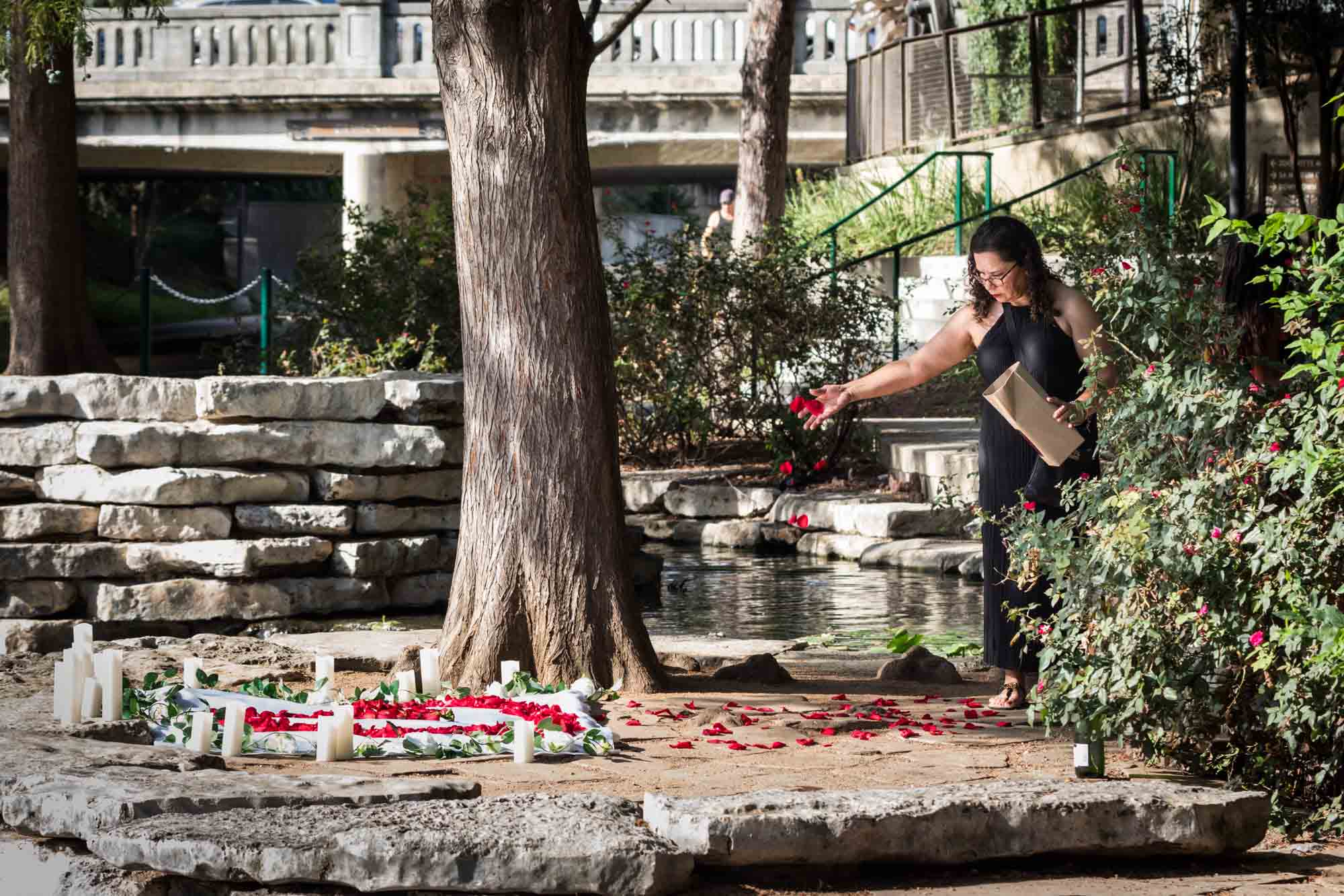 Woman scattering red rose petals on the ground at Pearl Springs