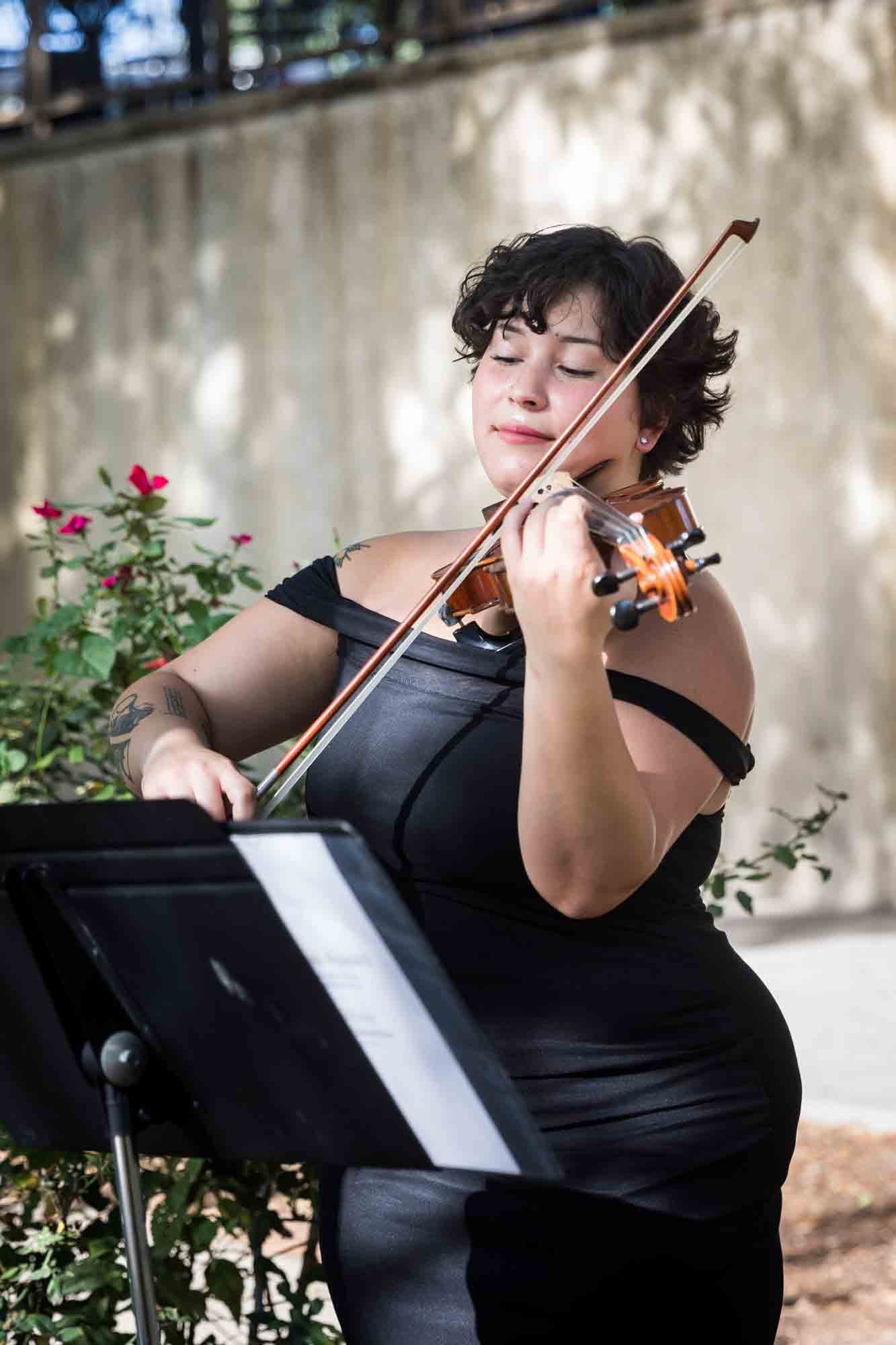 Female violinist wearing off shoulder black dress playing the violin at the Pearl