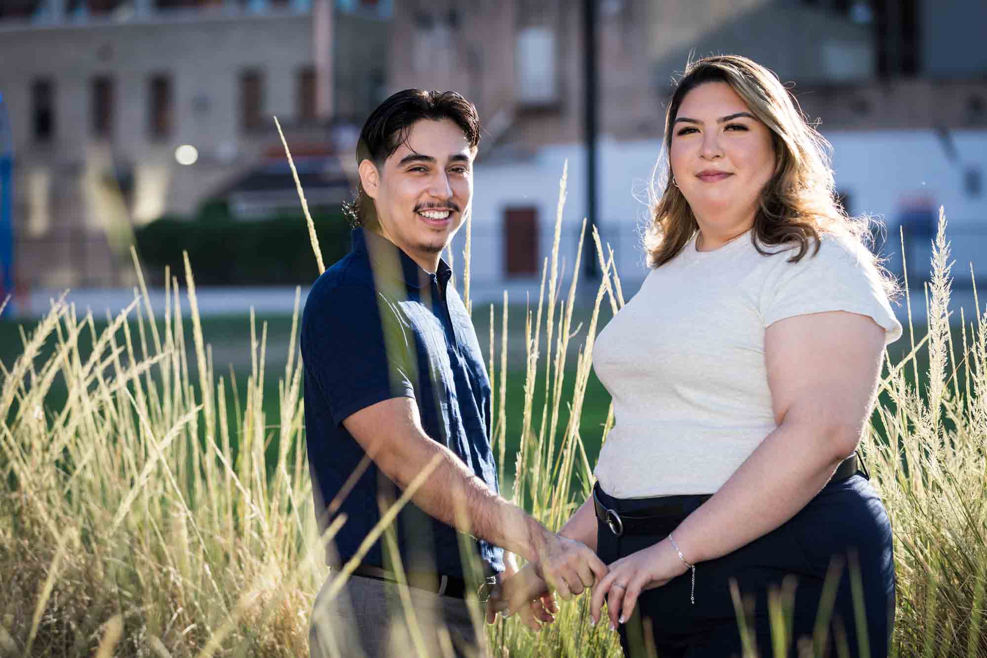 Couple holding hands in front of long bushes during a downtown San Antonio photo shoot