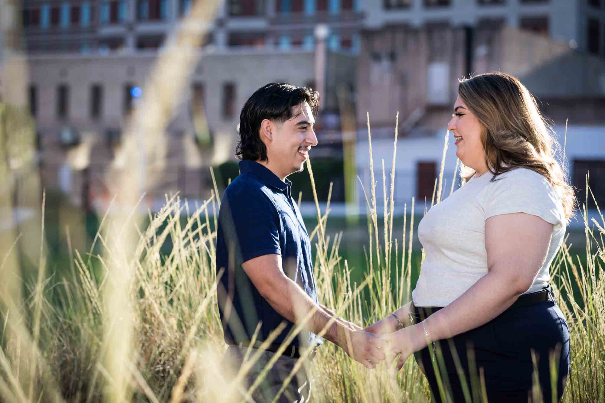 Couple touching in front of longCouple holding hands in front of long bushes during a downtown San Antonio photo shoot bushes during a downtown San Antonio photo shoot