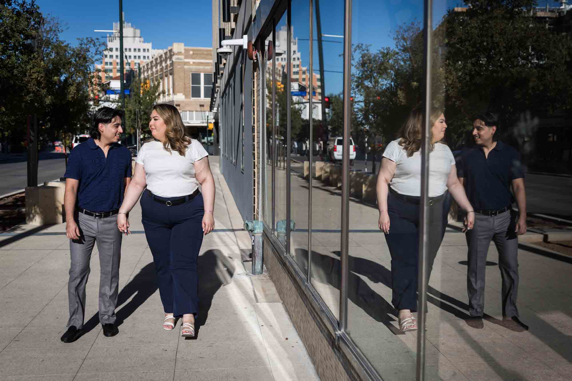 Couple walking in front of reflective windows during a San Antonio photo shoot