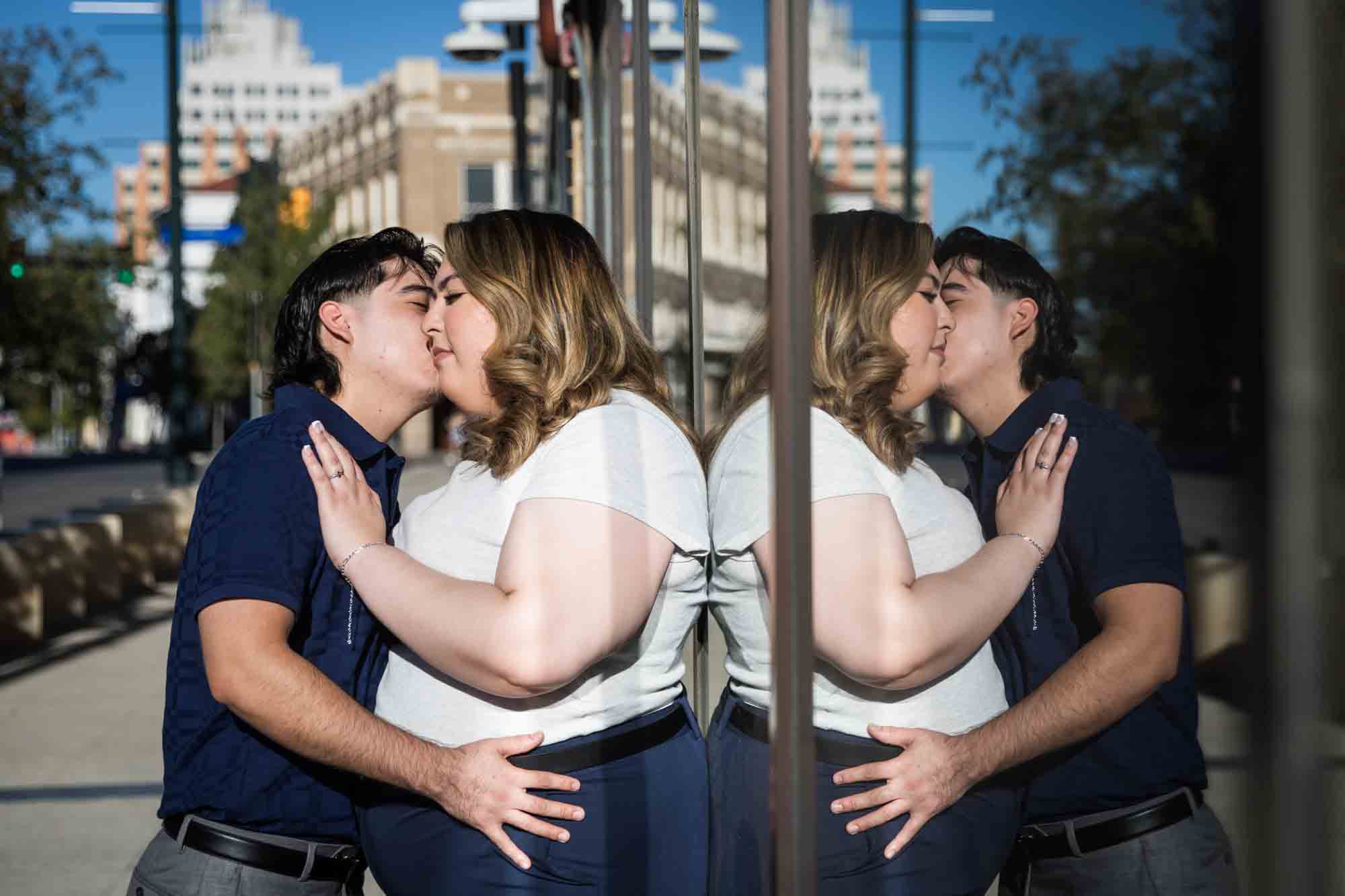 Couple kissing in front of reflective windows during a San Antonio photo shoot