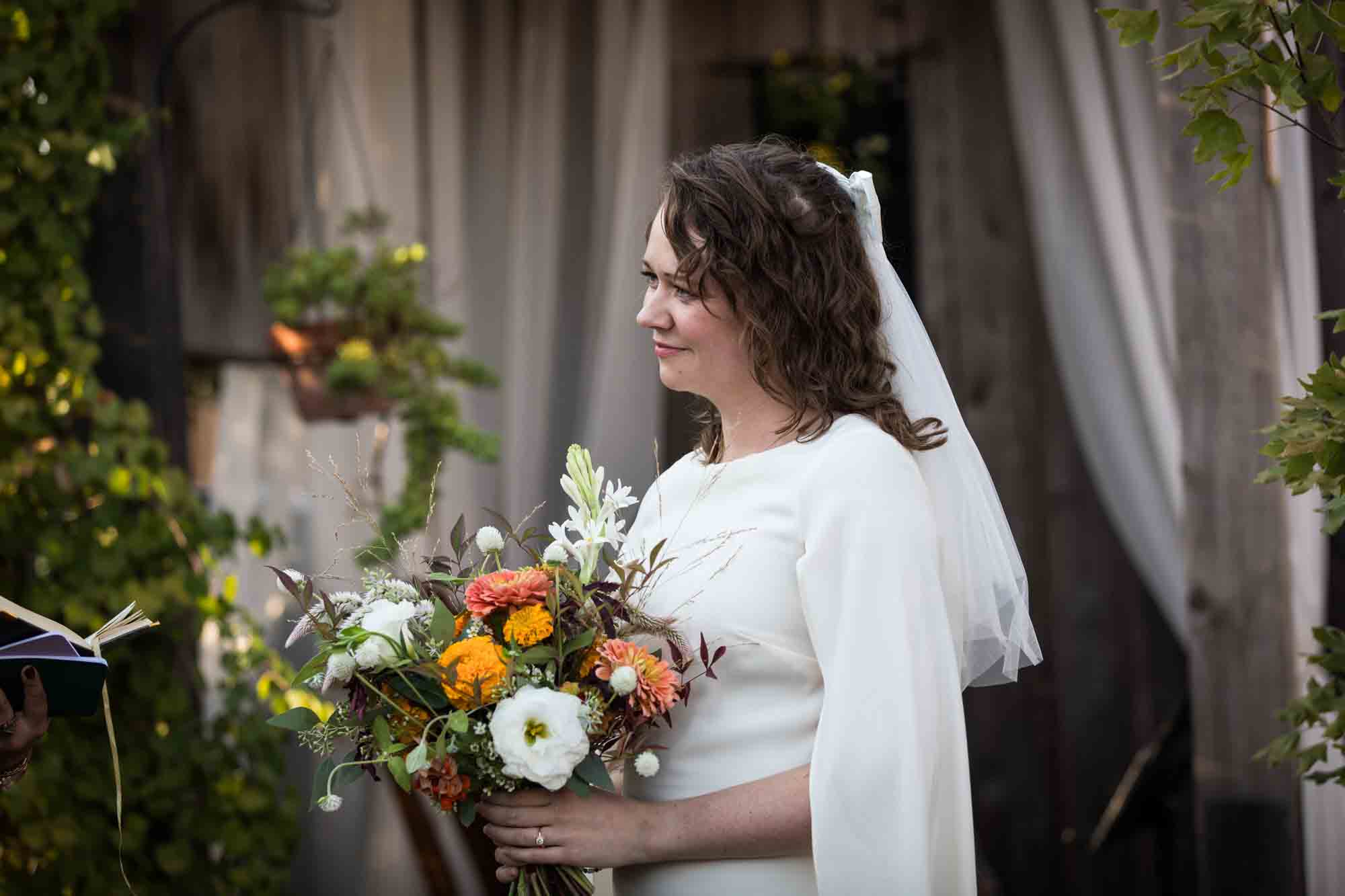 Bride wearing white dress and veil and holding colorful flower bouquet