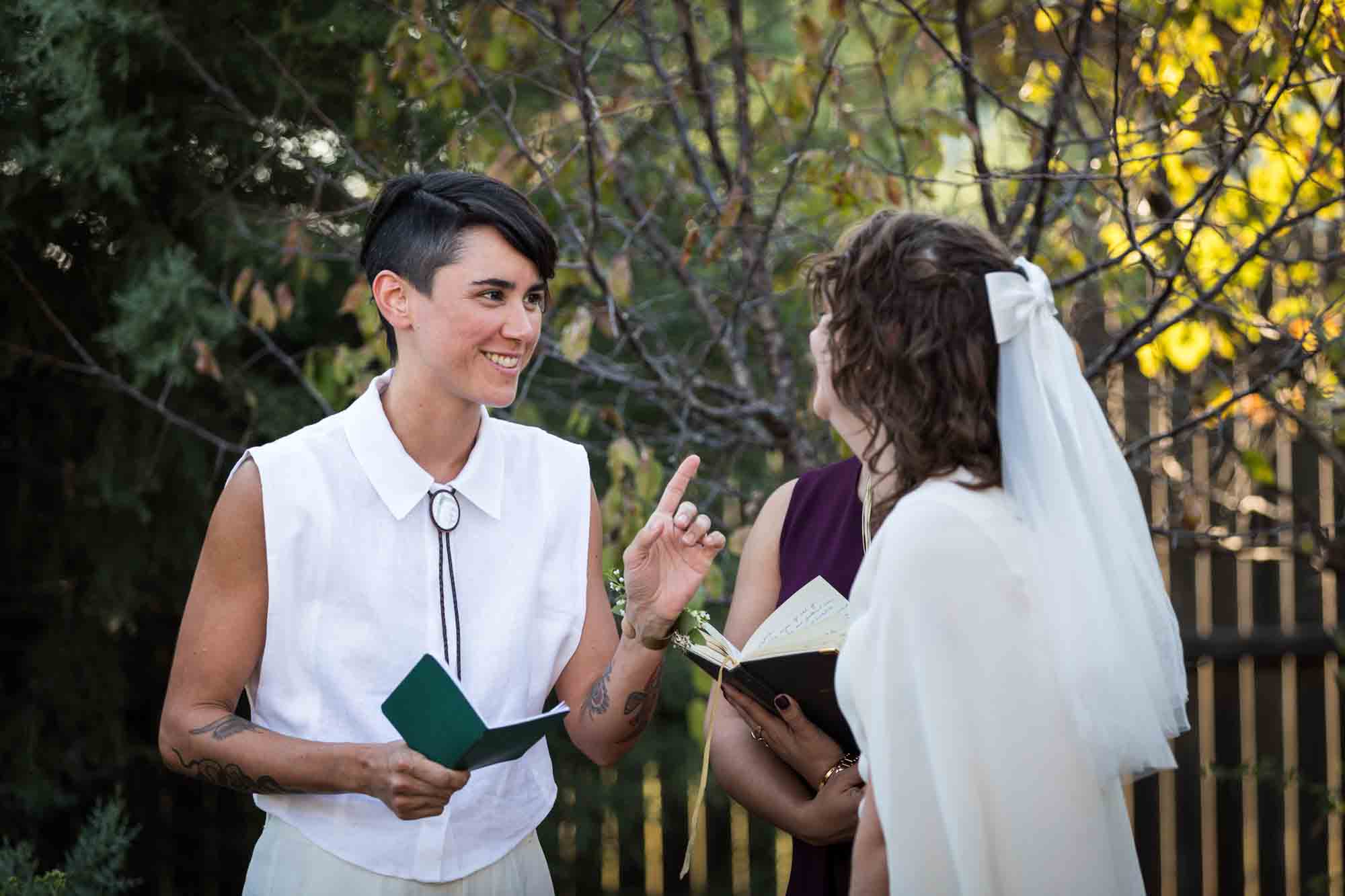 Two brides exchanting vows and laughing at a Boerne backyard wedding