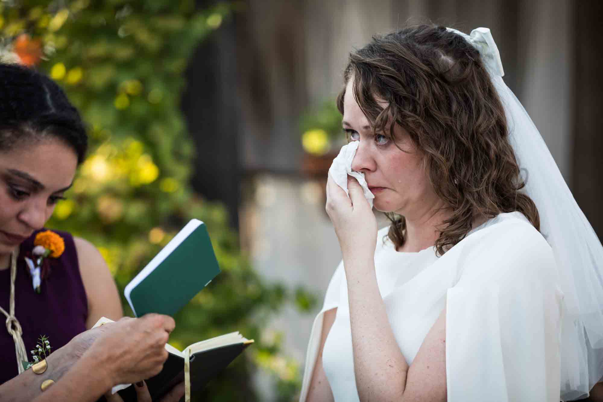 Bride wearing white dress wiping away tears at a Boerne backyard wedding