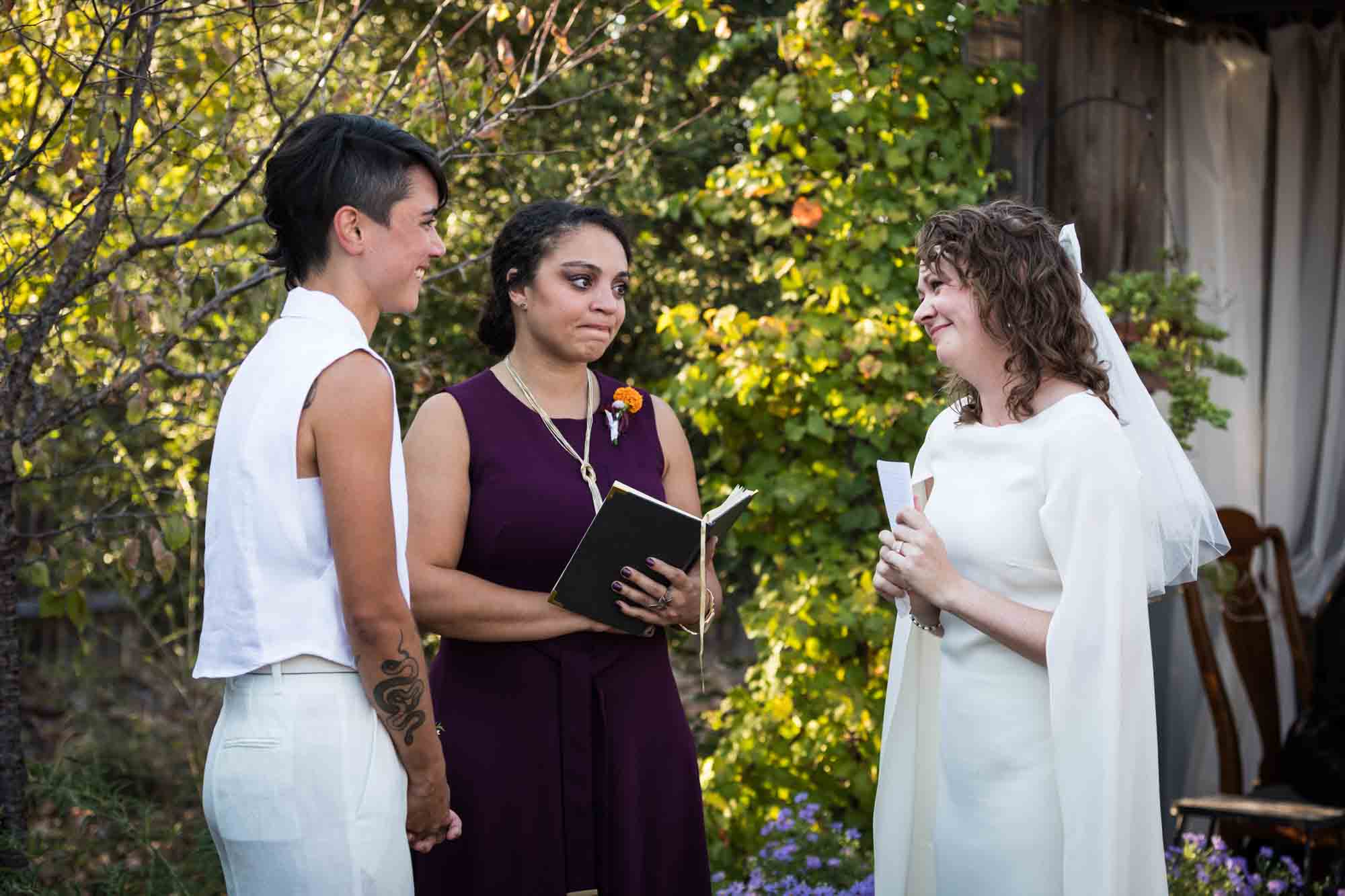 Two brides exchanging vows in front of officiant at a Boerne backyard wedding