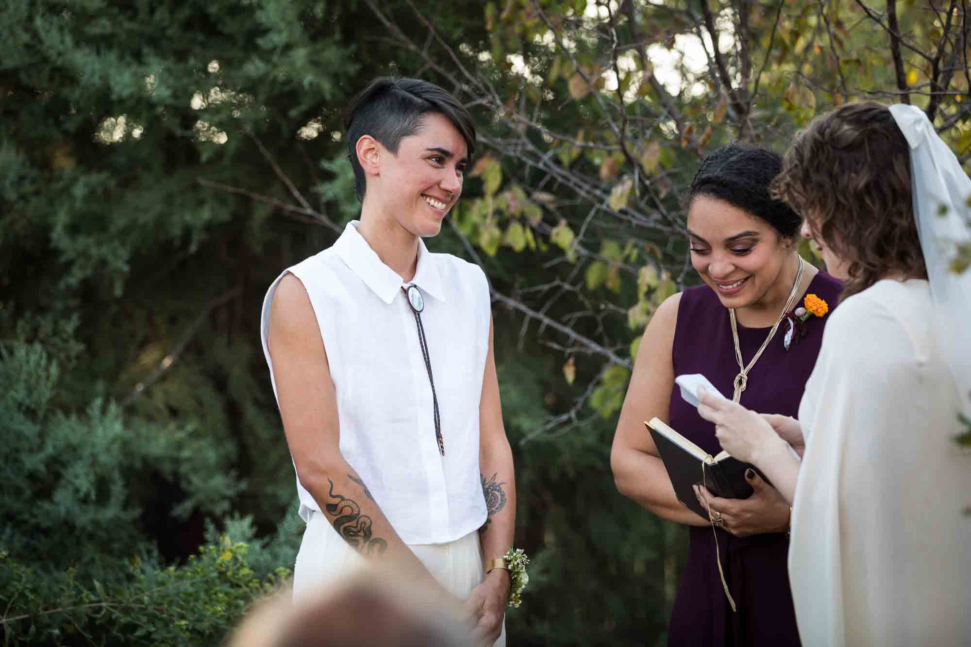 Two brides laughing in front of officiant at a Boerne backyard wedding