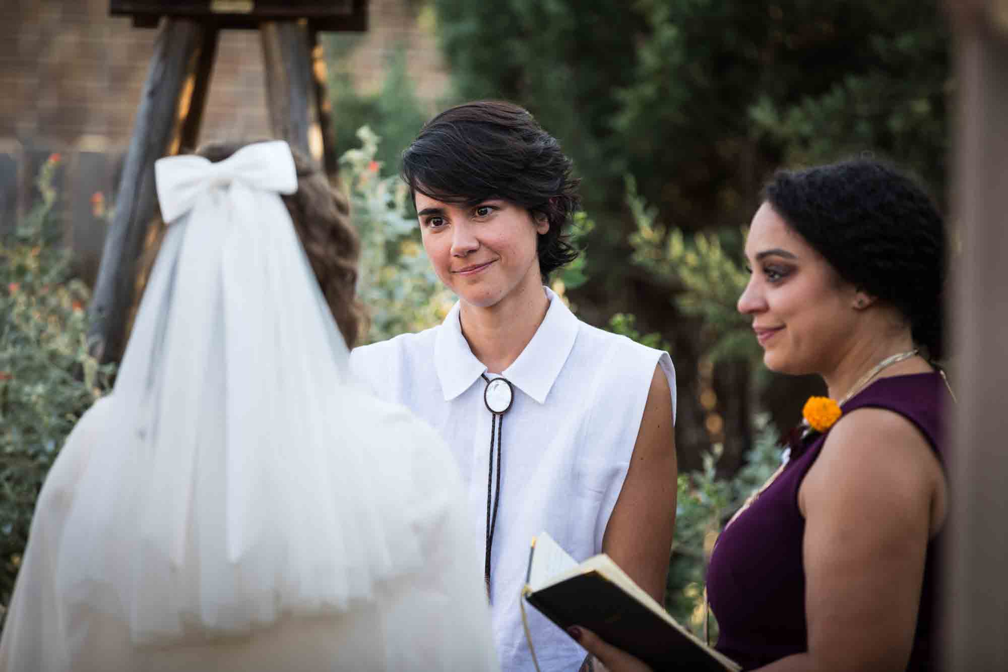 Two brides standing in front of officiant at a Boerne backyard wedding