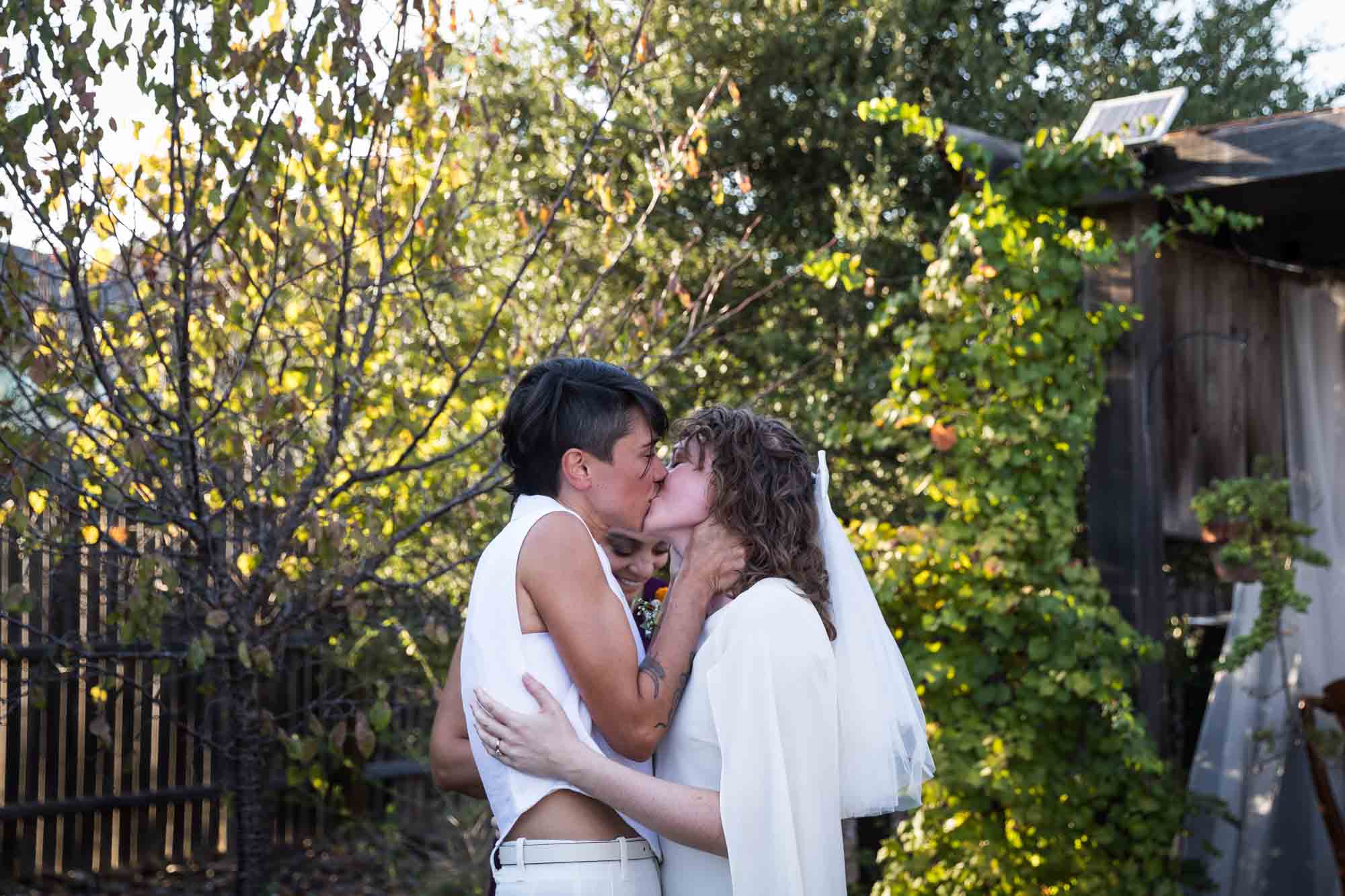 Two brides kissing after ceremony at a Boerne backyard wedding