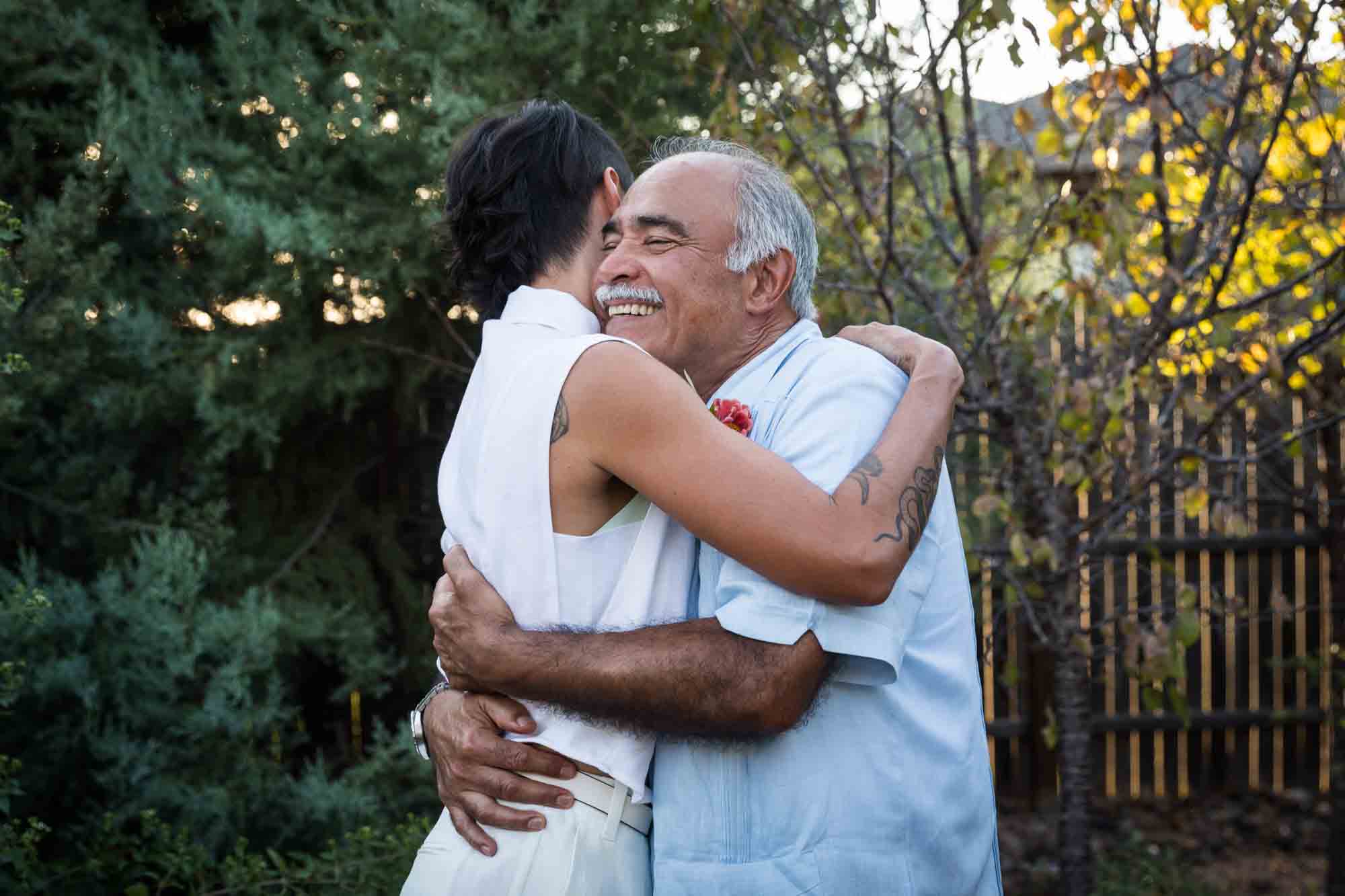 Bride hugging father with grey hair and mustache at a Boerne backyard wedding