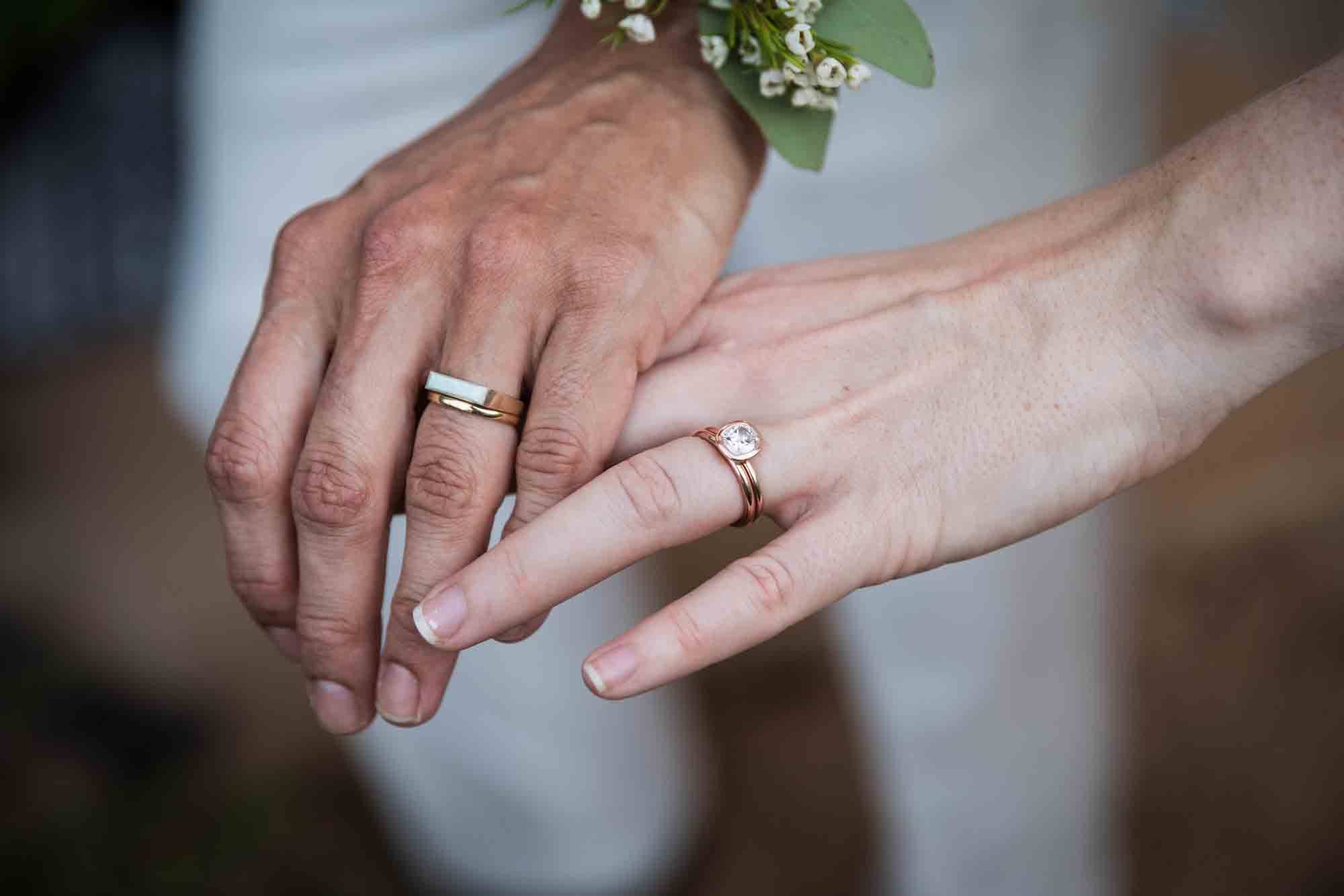 Close up of two women holding fingers and wearing wedding bands