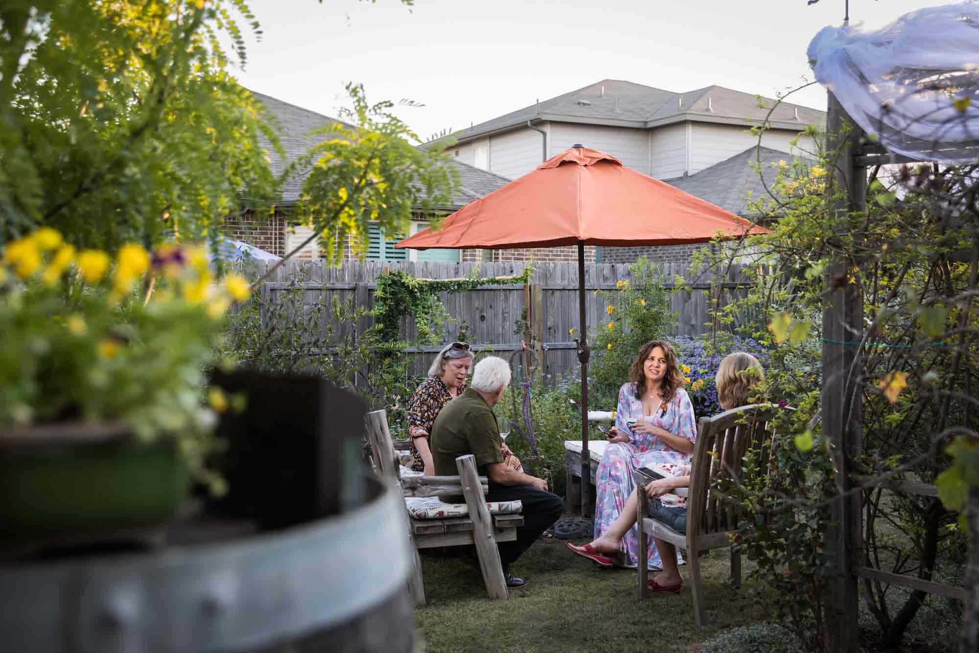 Guests seated outside under red umbrella at a Boerne backyard wedding