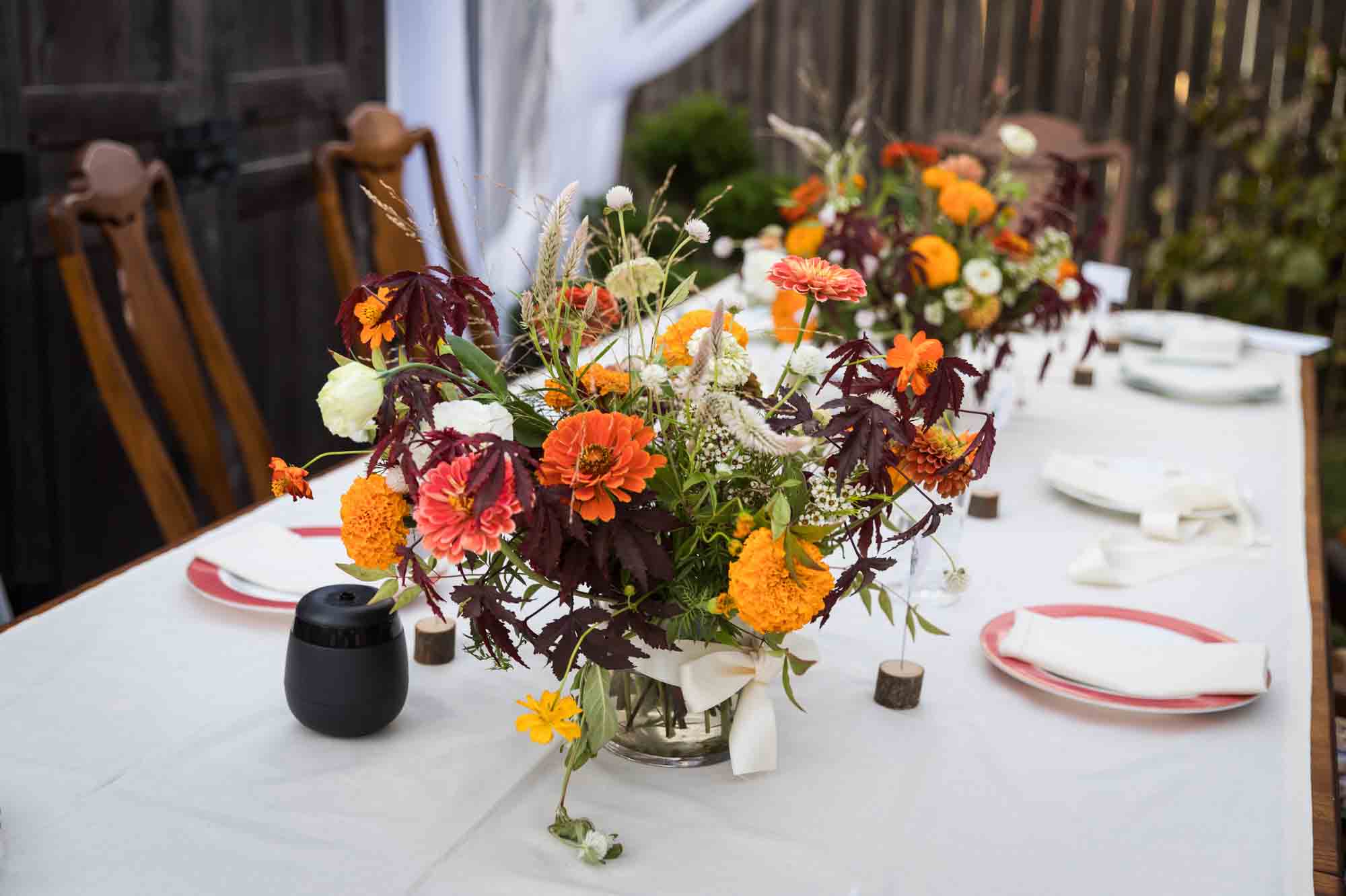 Table outside set with white tablecloth and beautiful flower bouquets