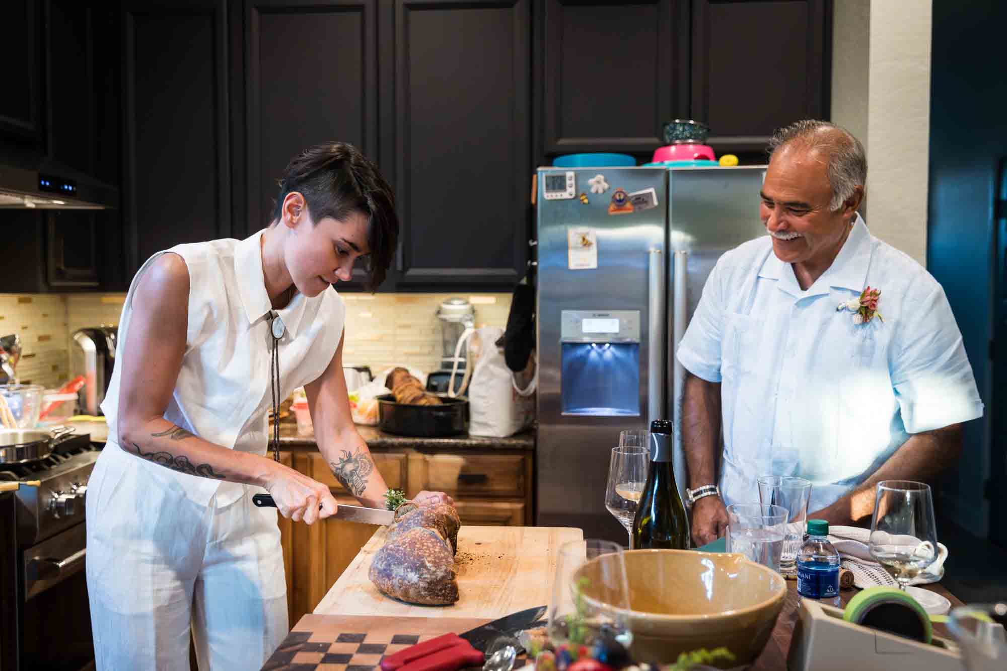 Woman cutting bread with father watching in the kitchen