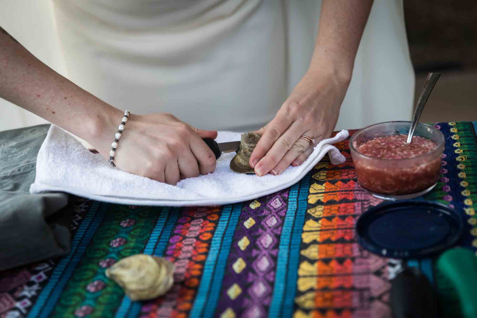 Close up of woman wearing white dress and shucking oysters