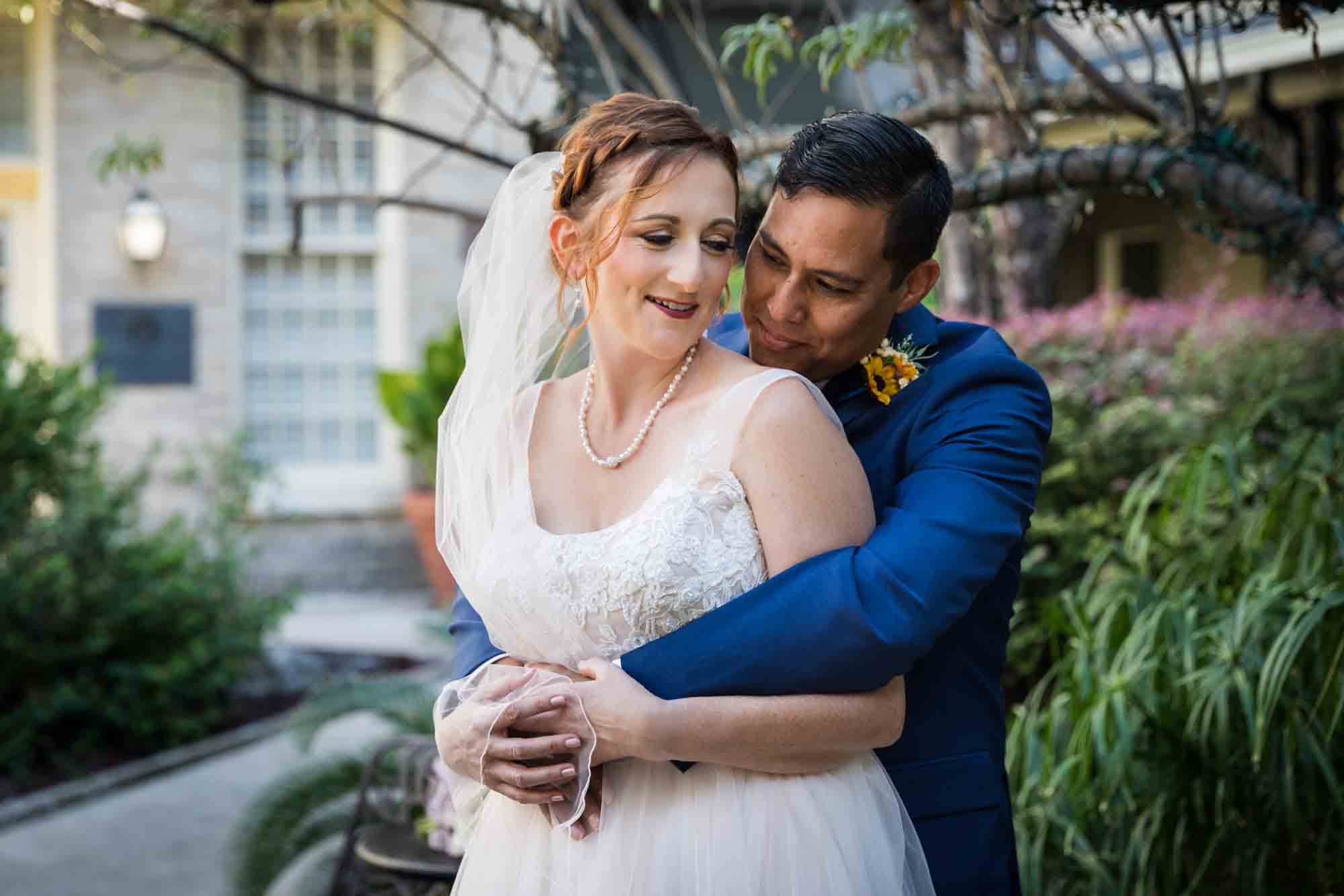 Bride and groom hugging in plant-filled courtyard at the Menger Hotel