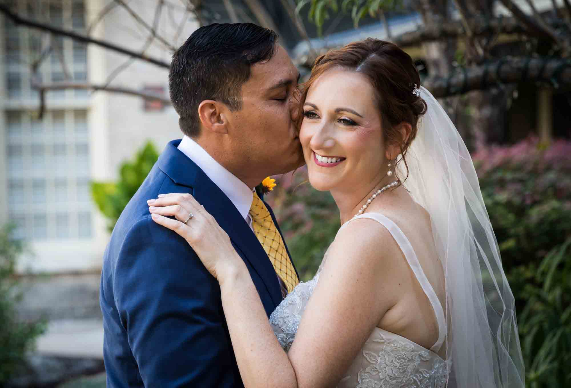 Bride and groom kissing in plant-filled courtyard at the Menger Hotel