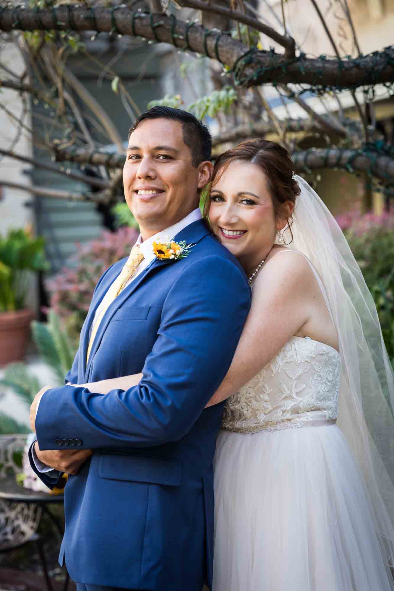 Bride and groom hugging in plant-filled courtyard at the Menger Hotel