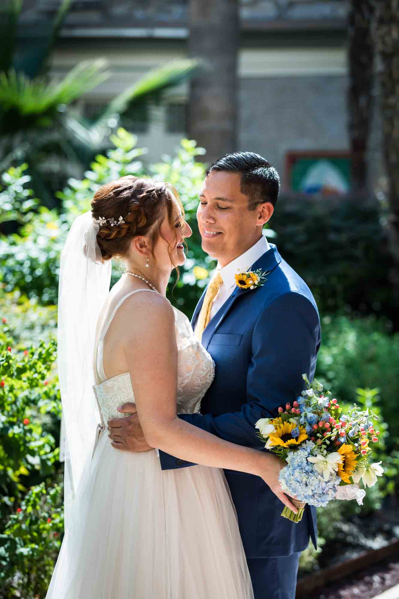 Bride and groom hugging in plant-filled courtyard at the Menger Hotel