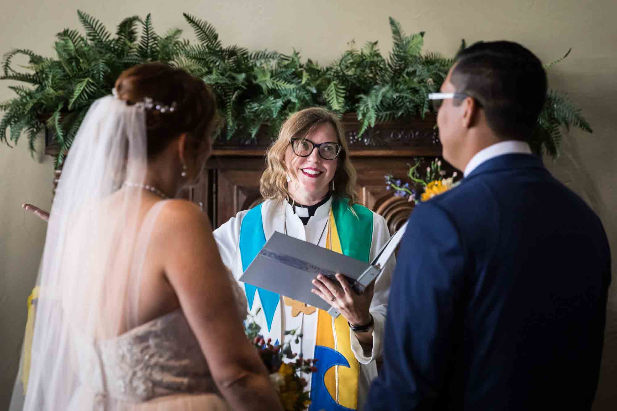 Pat O’Brien wedding photos of a pastor speaking to bride and groom during ceremony