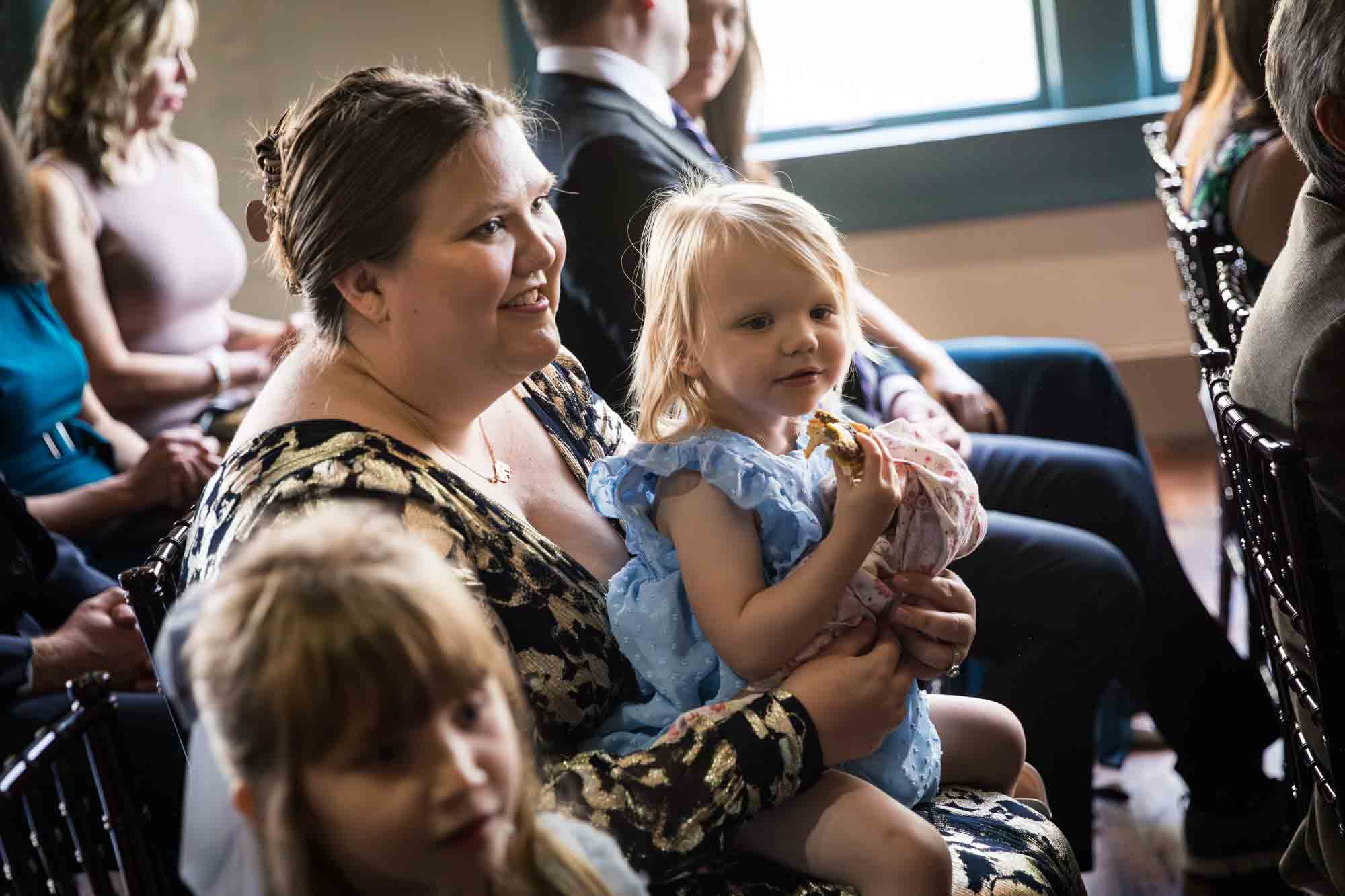 Mother with blonde little girl on her lap watching Pat O’Brien wedding ceremony