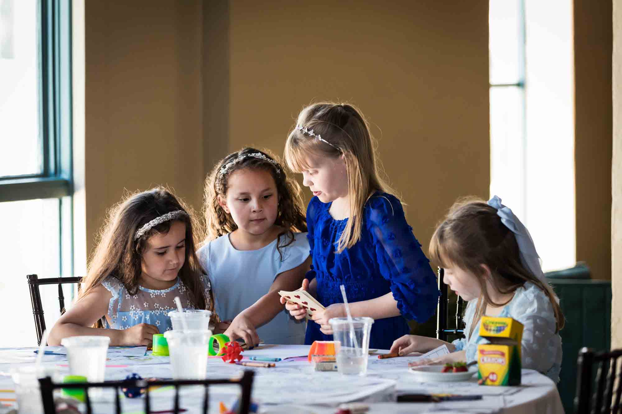 Pat O’Brien wedding photos of table surrounded by four little girls looking at toys and books