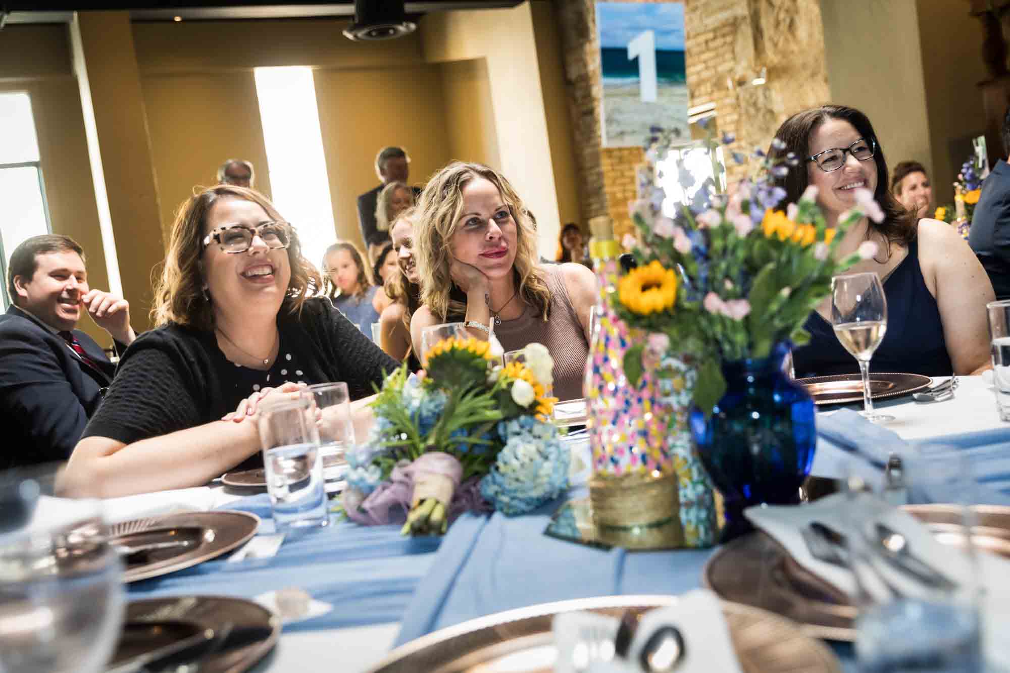 Pat O’Brien wedding photos of three female guests smiling during speeches while seated at tables