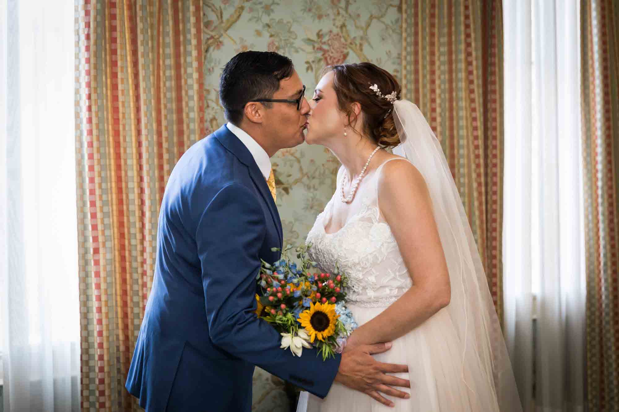 Bride and groom kissing in front of curtains at the Menger Hotel