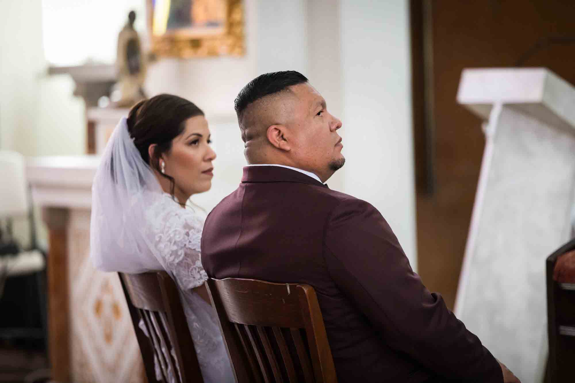 St. Henry Catholic Church wedding photos of bride and groom looking to the side while sitting in wooden chairs