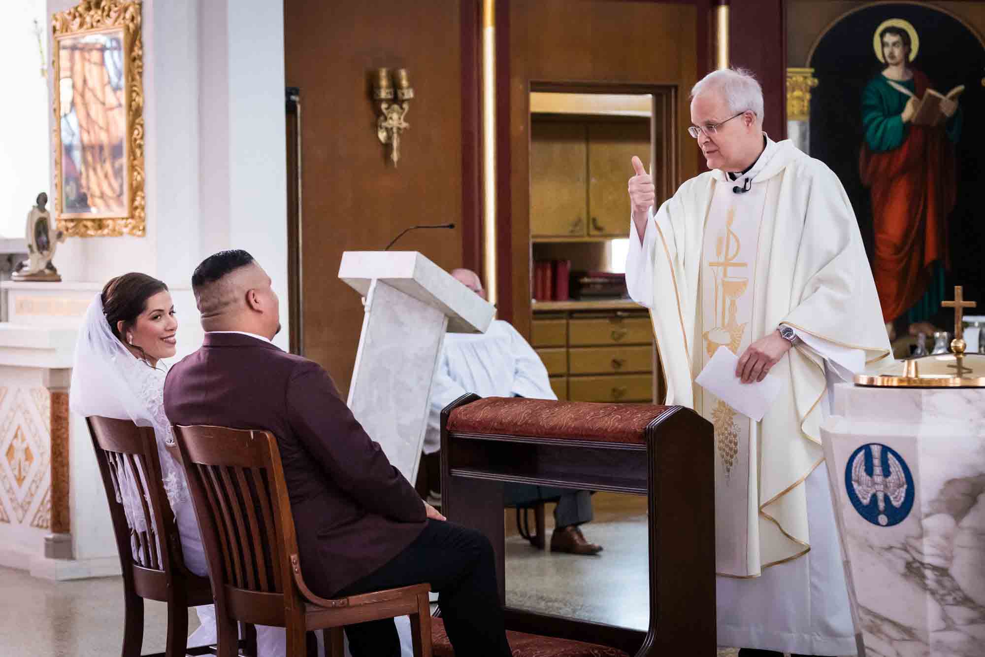 St. Henry Catholic Church wedding photos of priest giving 'thumb's up' sign to bride and groom during ceremony