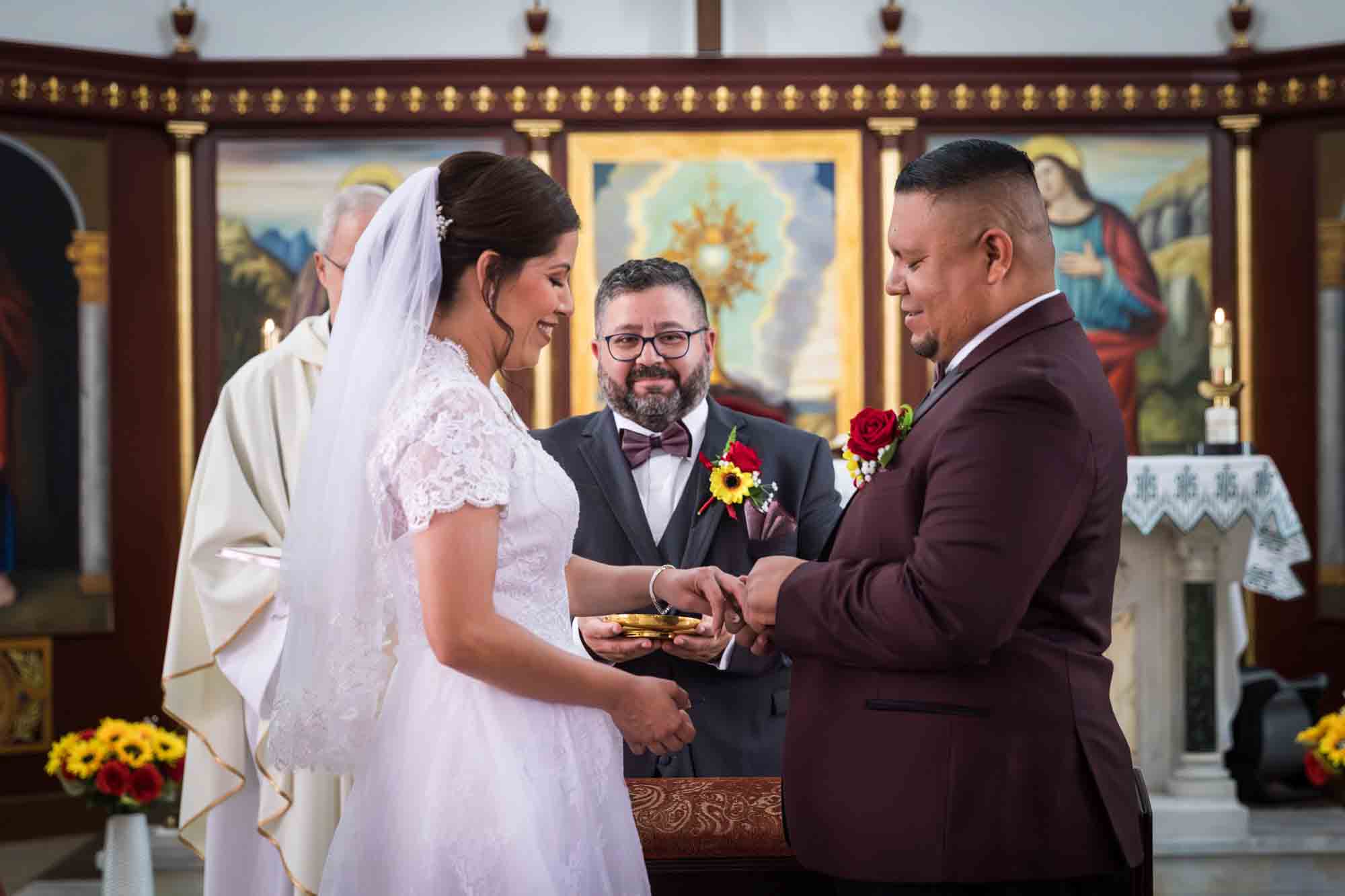 St. Henry Catholic Church wedding photos of groom putting ring on bride's finger at altar